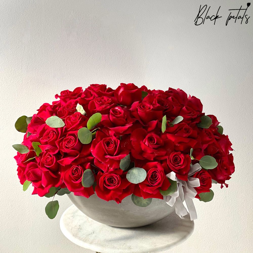 Roses Are Red Roses Are Red - 50 red roses are flexed delicately in this timeless arrangement.яSurprise your sweetheart with a floral shower filled with traditional red roses. Red is the color of love, the unprecedented symbolism of romance, undying love, and everlasting passion. Arrangement includes: Fresh Black Petal Signature Roses and Eucalyptus leaves BP Ceramic Vase Care instructions Custom greeting card DISCLAIMER - FRESH FLOWERS: These are fresh cut flowers and are perishable. Please follow care & instructions. Please note that if no variations from the list are chosen, you will receive the featured arrangement unless a substitution may need to be made based on the season, availability of flowers, or other unforeseen and uncontrollable circumstances occur. By making a purchase on this website, the customer authorizes substitutions within a specific color palette. Necessary substitutions to the arrangement will be at the designer?s discretion.