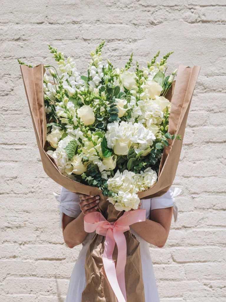 White wrapped Bouquet - An assortment of beautiful white flowers includes Roses, snap dragons, lilies, hydrangeas-stock, Mums, carations, alstrmerias and more 