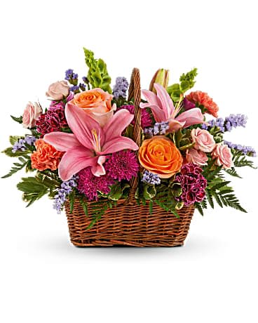 Blooming Joy Bouquet by Teleflora - Spread joy with this basket of bright blooms, featuring radiant roses and the prettiest pink lilies. This bouquet features orange roses, light pink spray roses, pink asiatic lilies, burgundy carnations, orange carnations, bells of Ireland, purple cushion spray chrysanthemums, blue sinuata statice, variegated pittosporum and leatherleaf fern. Delivered in a Rectangular Basket with Handle.