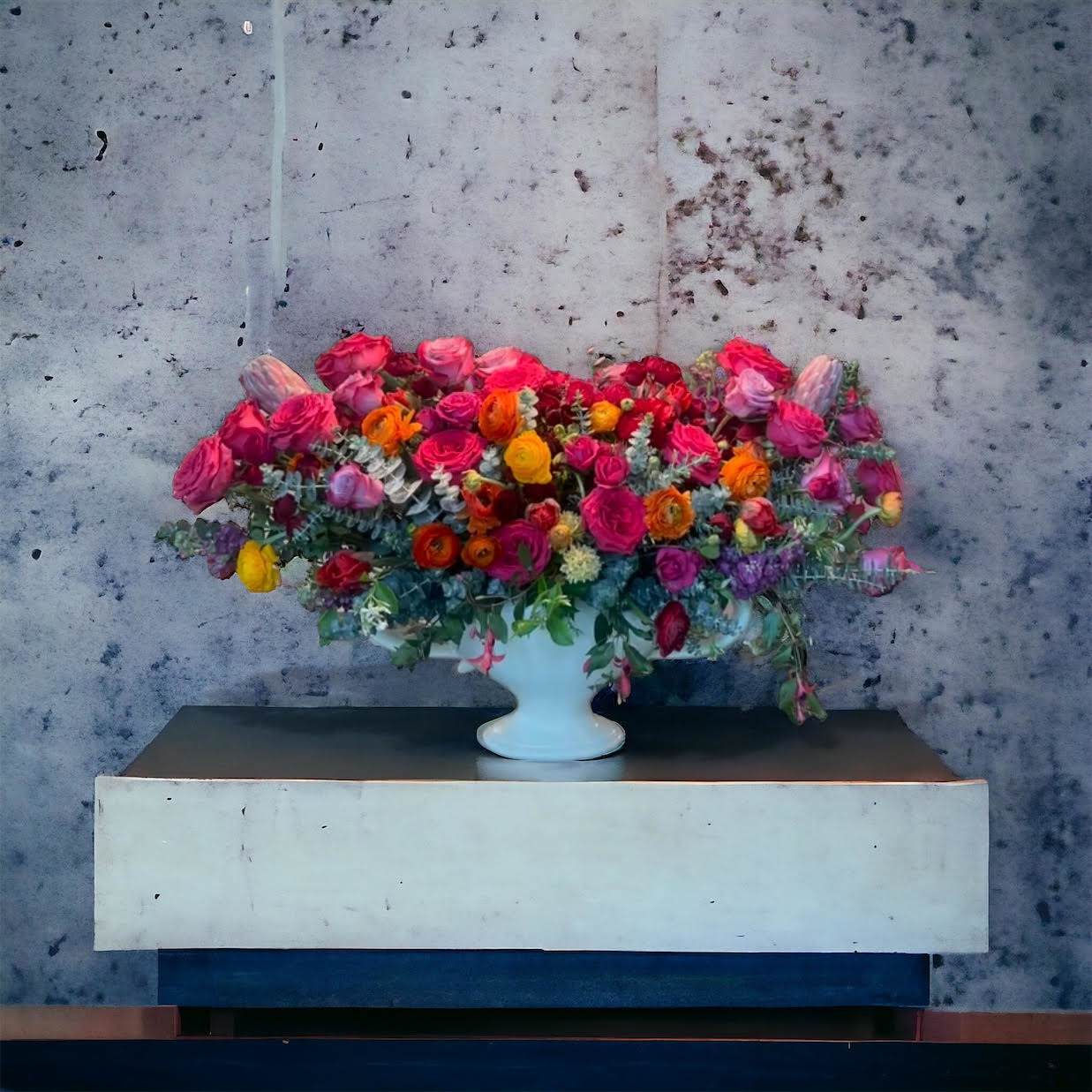 Boundless Beauty *Best Seller Boundless Beauty *Best Seller - A lush arrangement of jewel tone roses accompanied by pops of sunset colored ranunculus with draping eucalyptus greenery. This arrangement is absolutely stunning.