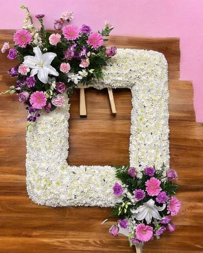 Picture in our memories -  ChatGPT Capture cherished memories with our stand picture frame adorned in serene white and gentle pink flowers. Each bloom delicately arranged, offering solace and a lasting tribute to celebrate a life well-lived. Honour their legacy with beauty and grace. Inside picture 16x20 not included Approx 24w x 30h