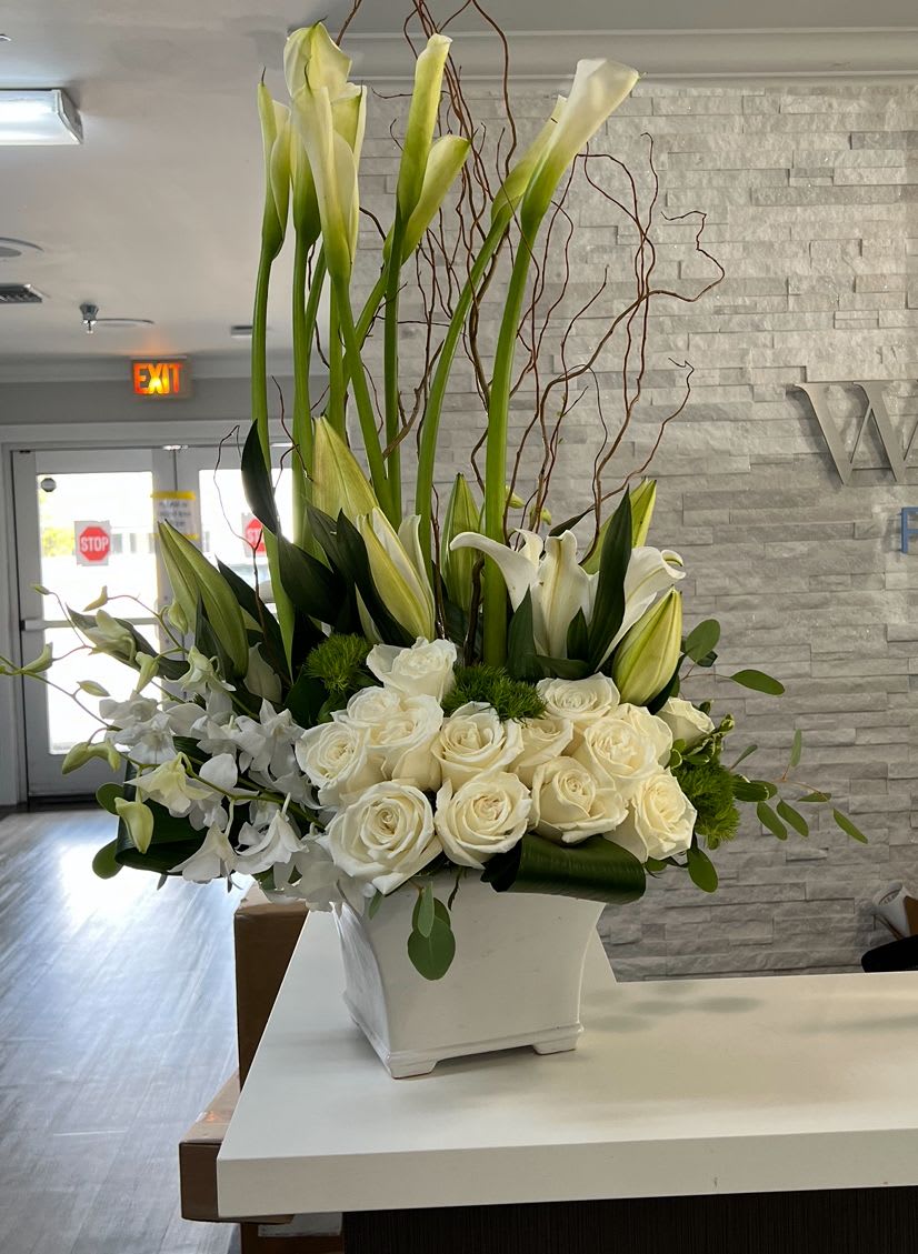 White Stems - One of the best seller arrangement in whites Calla lilies, orchids, roses, snaps and more of the freshest flowers in a white ceramic container 