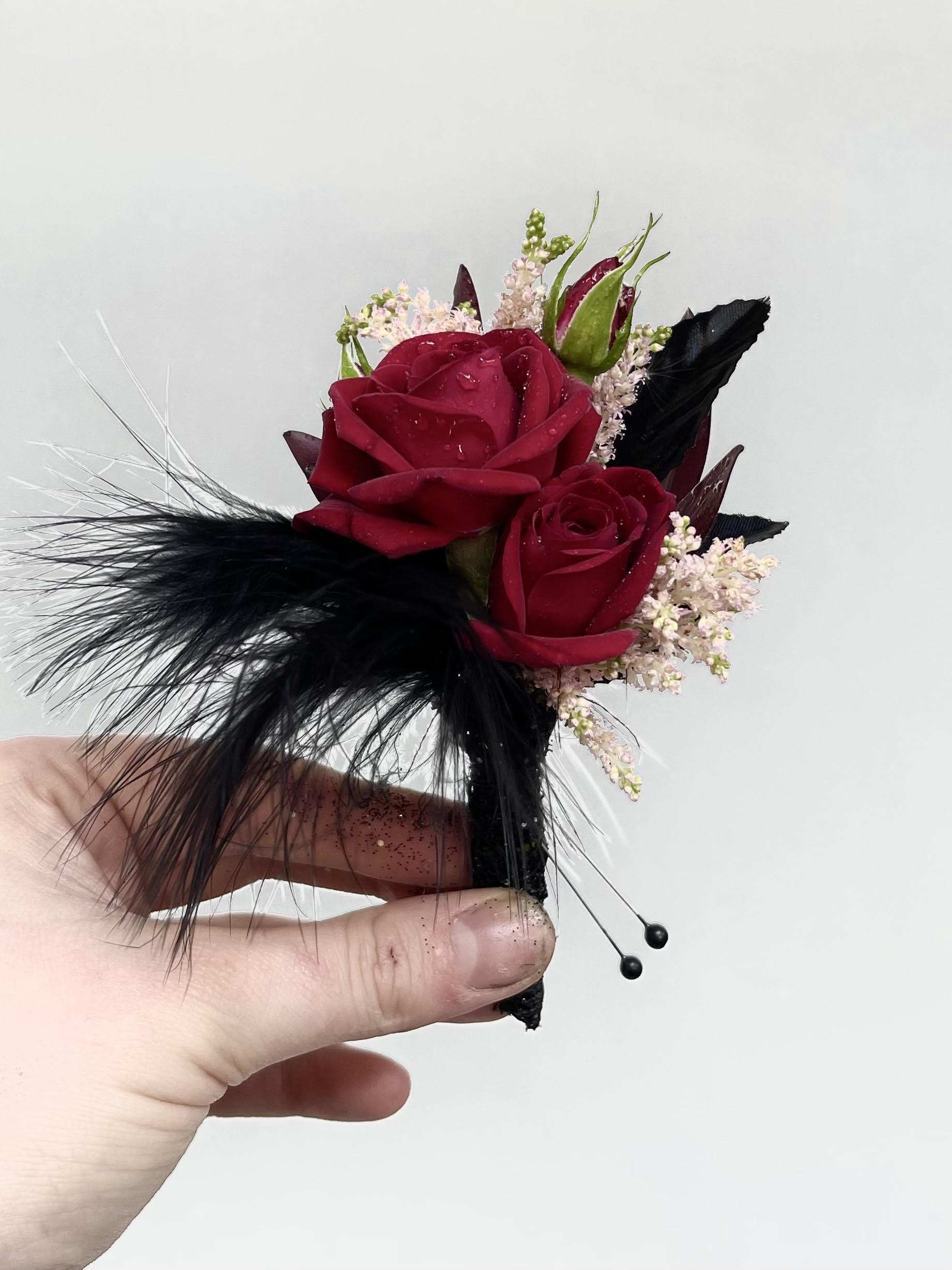 Red Men's Boutionnere Red Men's Boutionnere - Red spray roses (or your choice of color) accented with seasonal flowers feathers and gems. Choose color, accents and or size small (25) medium (30) or large (35).