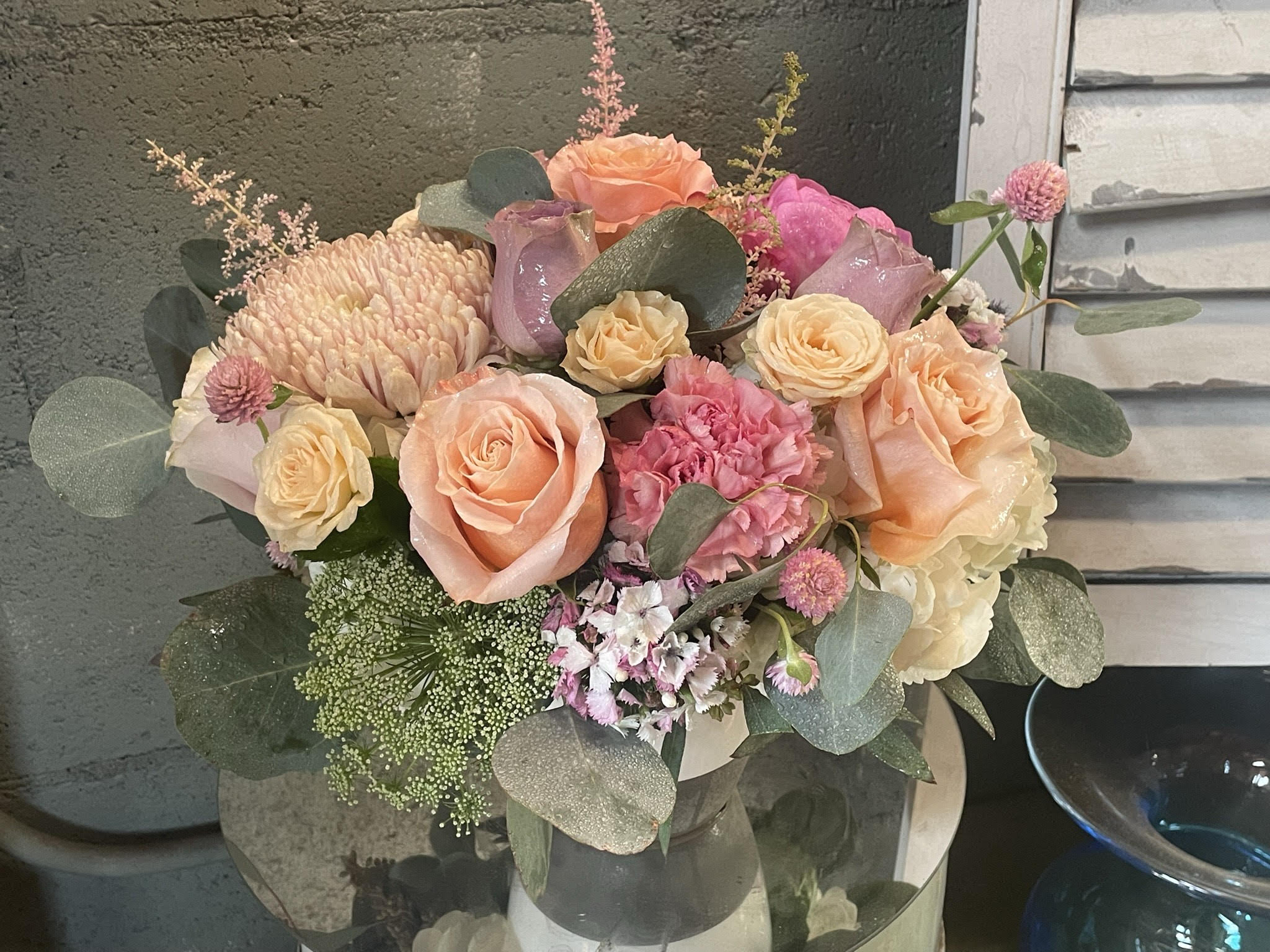 Seashell  - A mix of creams, corals, and textured greens for a cottage by the sea mood always. Arranged in a 5x6 ceramic vase and includes caramel carns, cremones, roses, green mist, spray roses, seasonal filler, and hydrangea. 