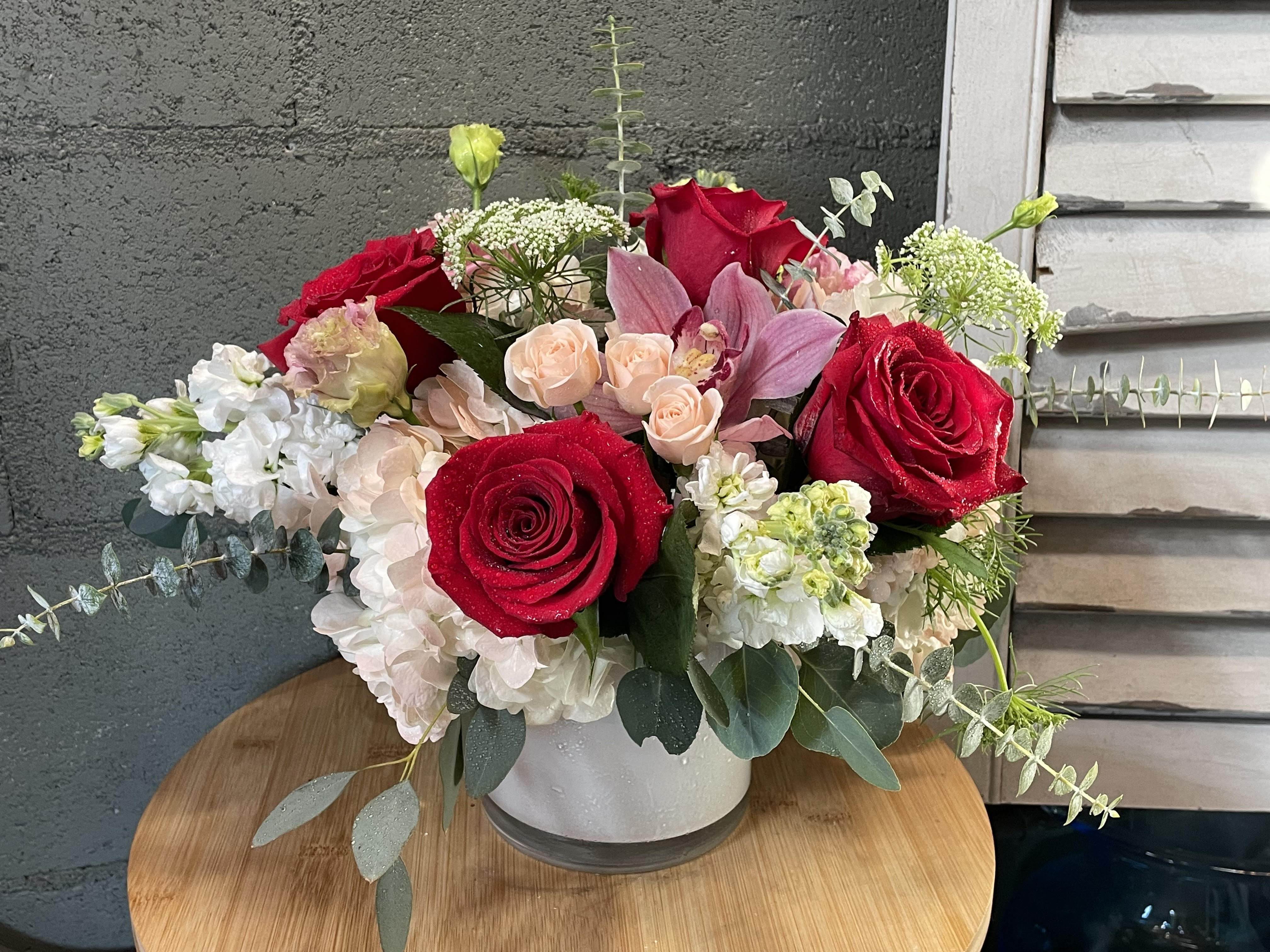 Sweet Embrace - Give someone a Sweet Embrace to let them know how you feel. Sweet Embrace is composed of blush pinks and white with a pop of red roses, orchids, Hydrangea, spray roses, and seasonal stock accents in a 5 inch x 5 inch cylinder vase. 