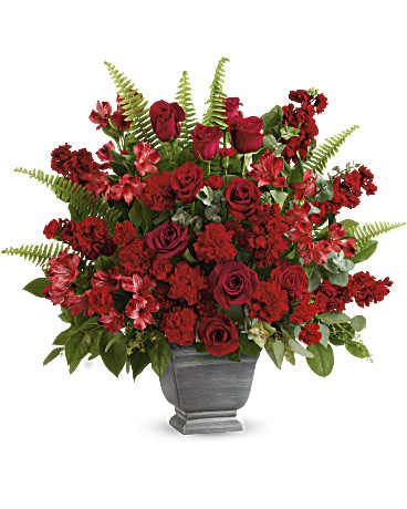 Teleflora's Bold Tribute Bouquet - Flowers for a funeral, Bold and beautiful, this majestic mix of red roses and fresh greens in a large, stone-inspired pot is a show of strength and support. Red roses, red alstroemeria, red carnations, miniature red carnations, and burgundy stock are arranged with spiral eucalyptus, seeded eucalyptus, sword fern, and lemon leaf. Delivered in Teleflora's Modern Heritage pot. Orientation: One-Sided
