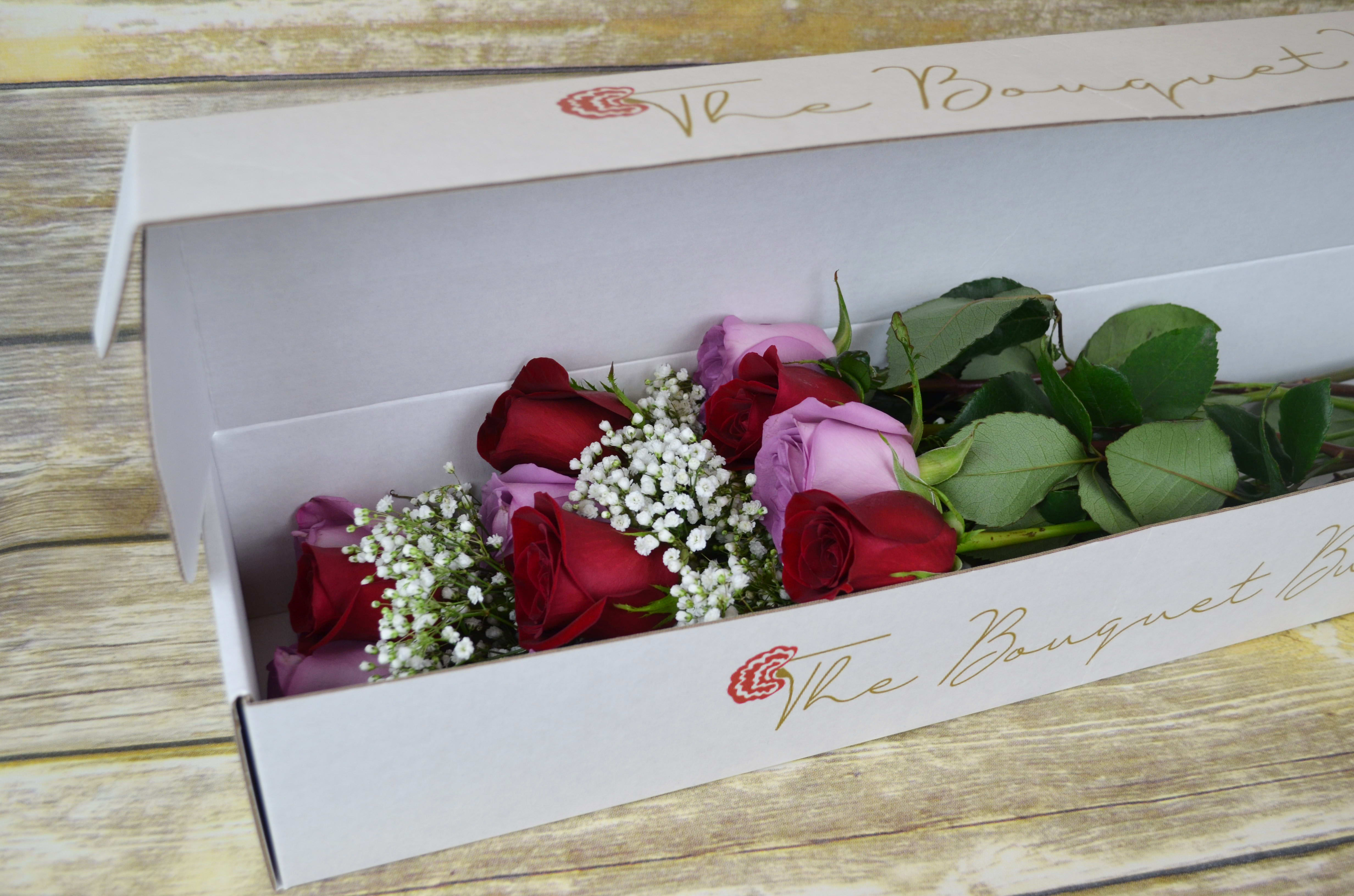 Love at First Sight - Boxed  - The perfect blend of sentiment and beauty, red and lavender roses say it all. All bouquets are arranged by our professional floral design team accented with seasonal filler (i.e. greenery, baby’s breath, etc.) inside a gift box. Blooms are hand delivered in person to enhance any celebration or a “just because” surprise. Our team selects the freshest flowers available, so shade of rose may vary due to seasonal availability. 