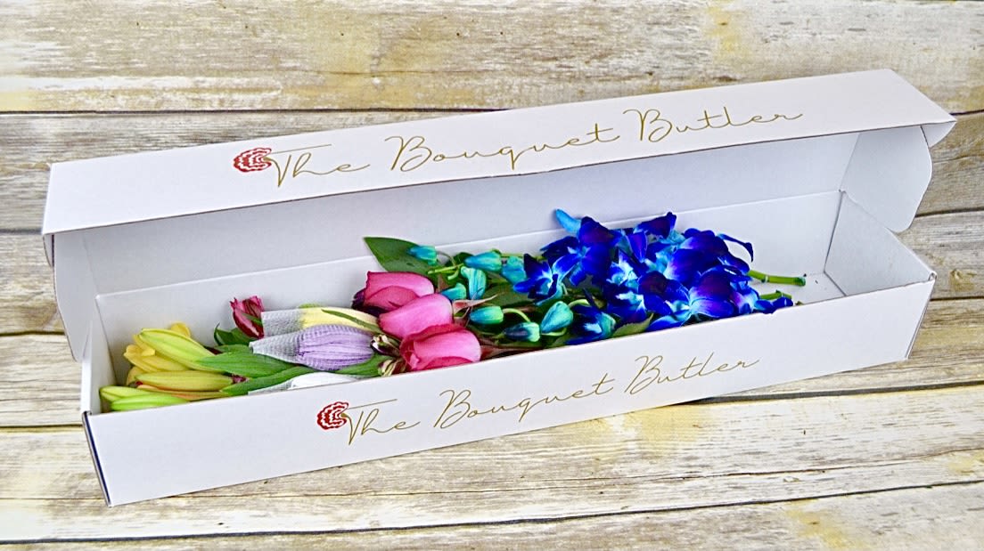 Euphoria - Boxed - This stunning blend of color causes a trance-like feel with a mix of lilies, roses, alstroemeria, chrysanthemums and exotic blue bom dendrobium orchids imported from Thailand. All bouquets are arranged by our professional floral design team accented with seasonal filler (i.e. greenery, baby’s breath, etc.) inside a gift box. Blooms are hand delivered in person to enhance any celebration or a “just because” surprise. Our team selects the freshest flowers available, so shade of flowers may vary due to seasonal availability.   *This bouquet includes specialty flowers, therefore they will require a 7 day minimum order date.