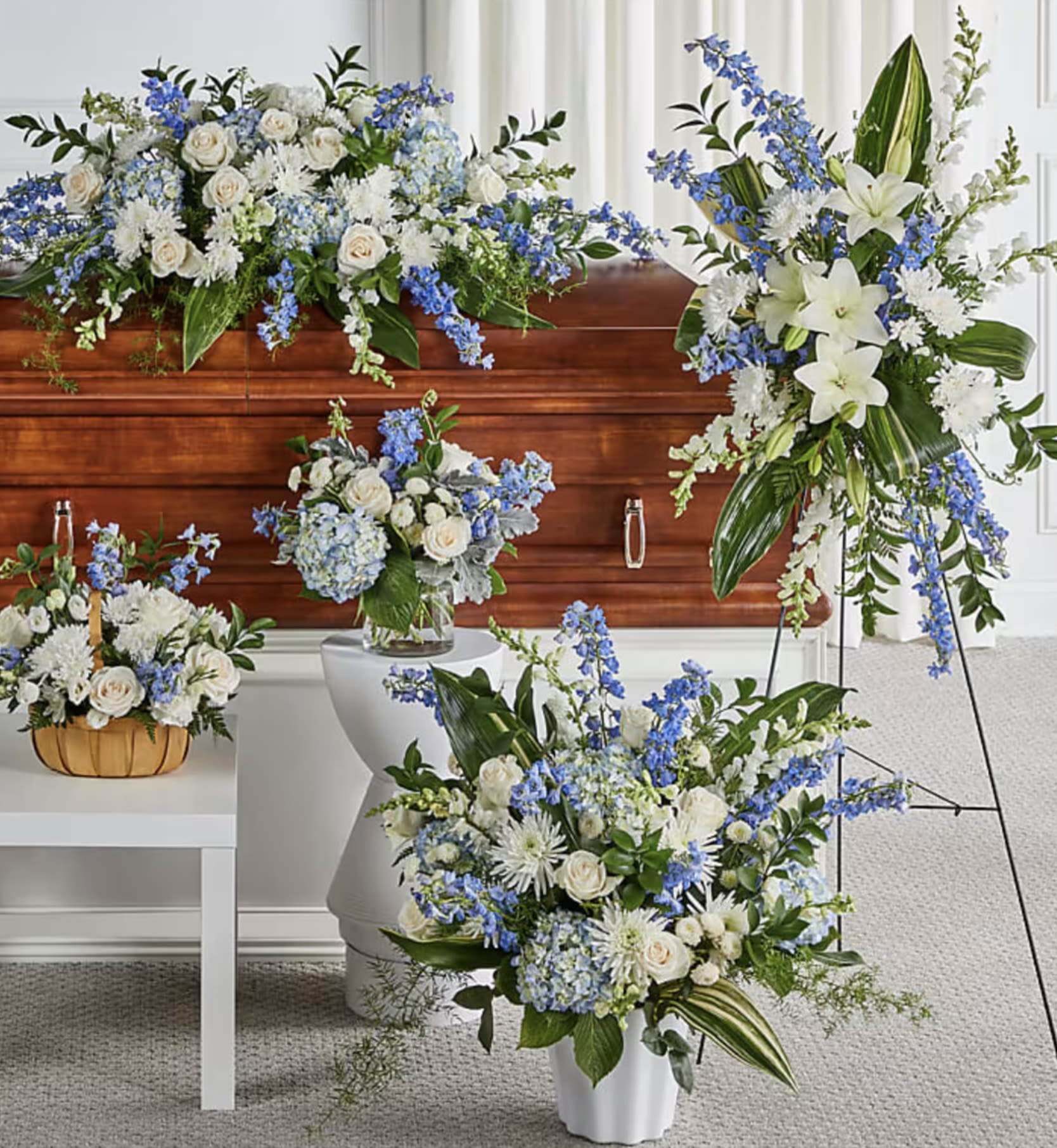 Blue Set Memories flowers  - Honor Their Memory with Serenity and Grace   Introducing our Tranquil Blue and White Sympathy Collection – a soothing blend of delicate blue hydrangeas, roses, lilies, and white accents. This elegant arrangement conveys peace, comfort, and loving remembrance, perfect for celebrating a life filled with grace.   Collection Includes: 	•	Casket Spray: A sophisticated design of blue and white blooms for a heartfelt farewell. 	•	Standing Spray: A towering tribute of lilies and blue accents symbolizing eternal peace. 	•	Basket Arrangement: A charming mix of flowers in a rustic basket for a personal touch. 	•	Floral Vase Arrangement: A graceful bouquet for the service or home.  Share your condolences with this serene and timeless collection. Let us help you create a meaningful tribute that brings comfort and beauty. Contact us for customization today.