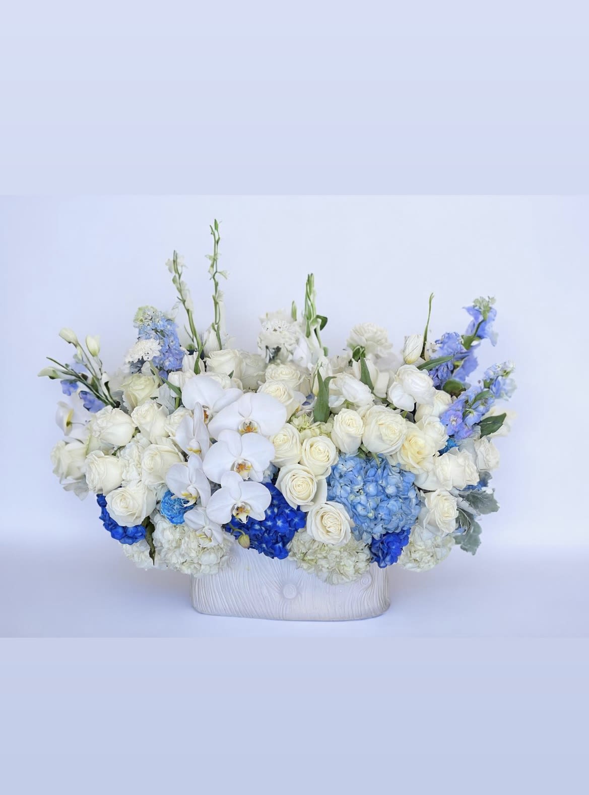Blue River - and elegant explosion of blue hydrangea, white roses, calla lilies, and luxurious white phalaenopsis orchids.