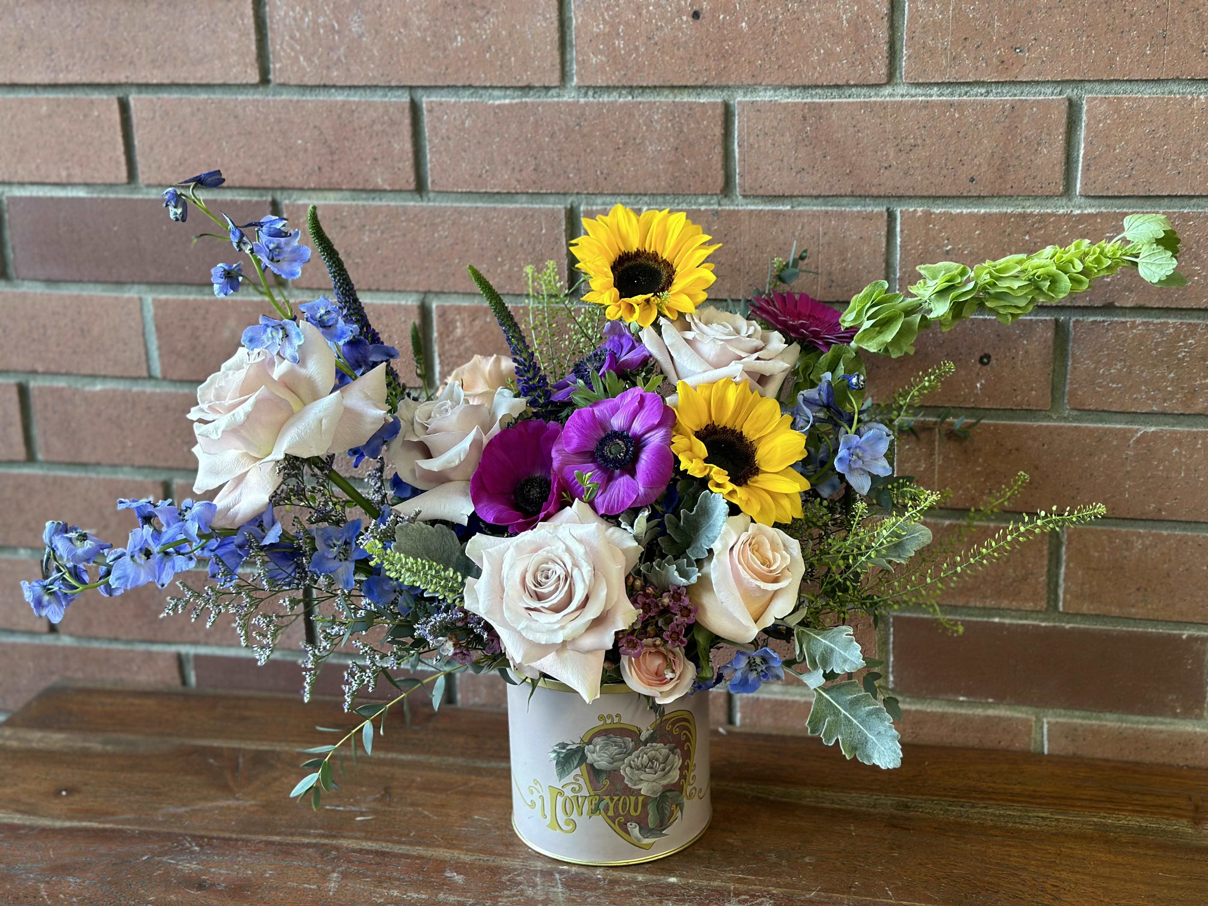 Garden of Love - Roses, Sunflowers, Daisies, Anemones, Bells of Ireland, Delphinium, and lush filler in a tin can that says &quot;I love you.&quot;