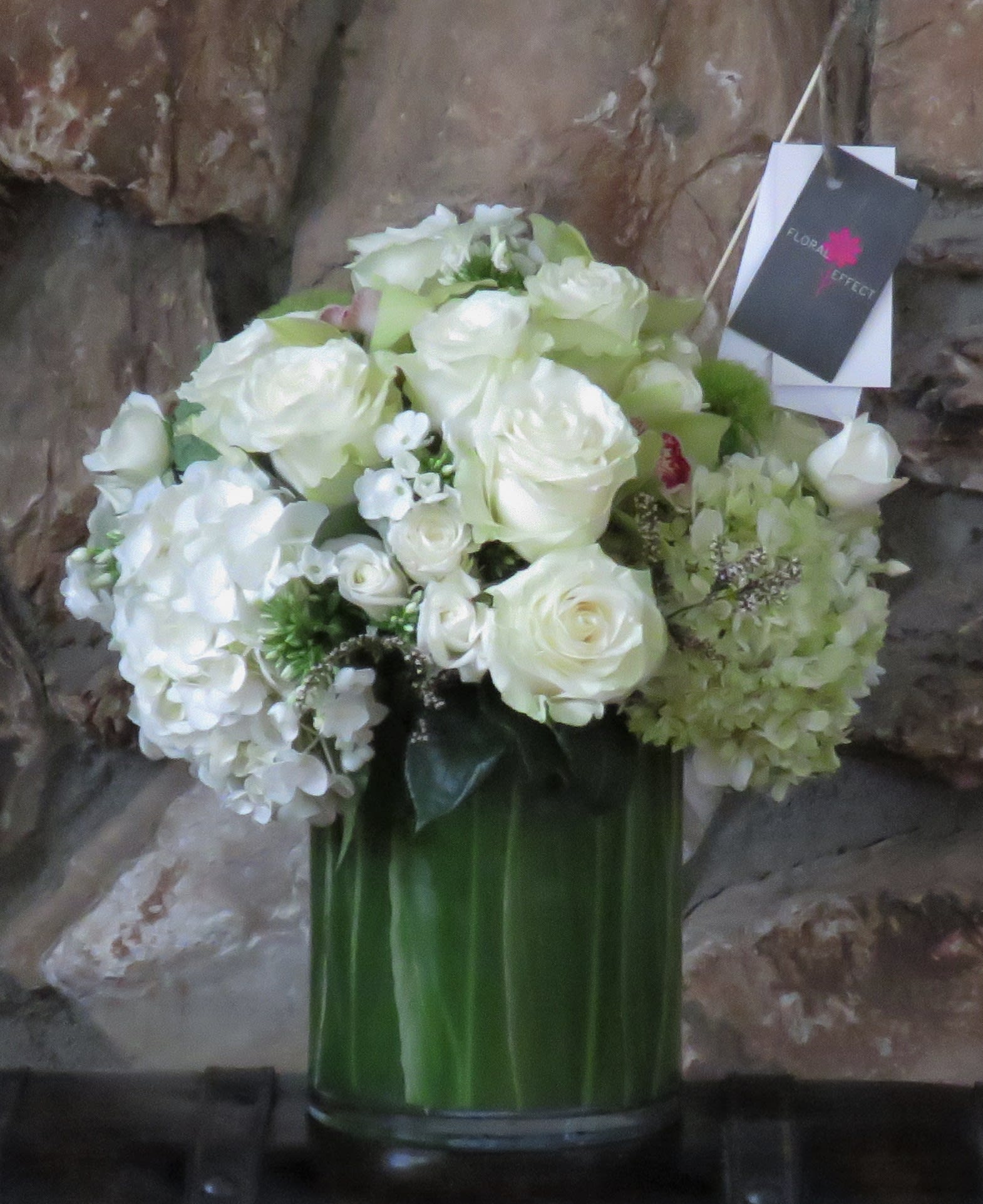 White and Green White and Green - Roses, Hydrangeas, Orchids, and seasonal flowers arranged in a glass vase.