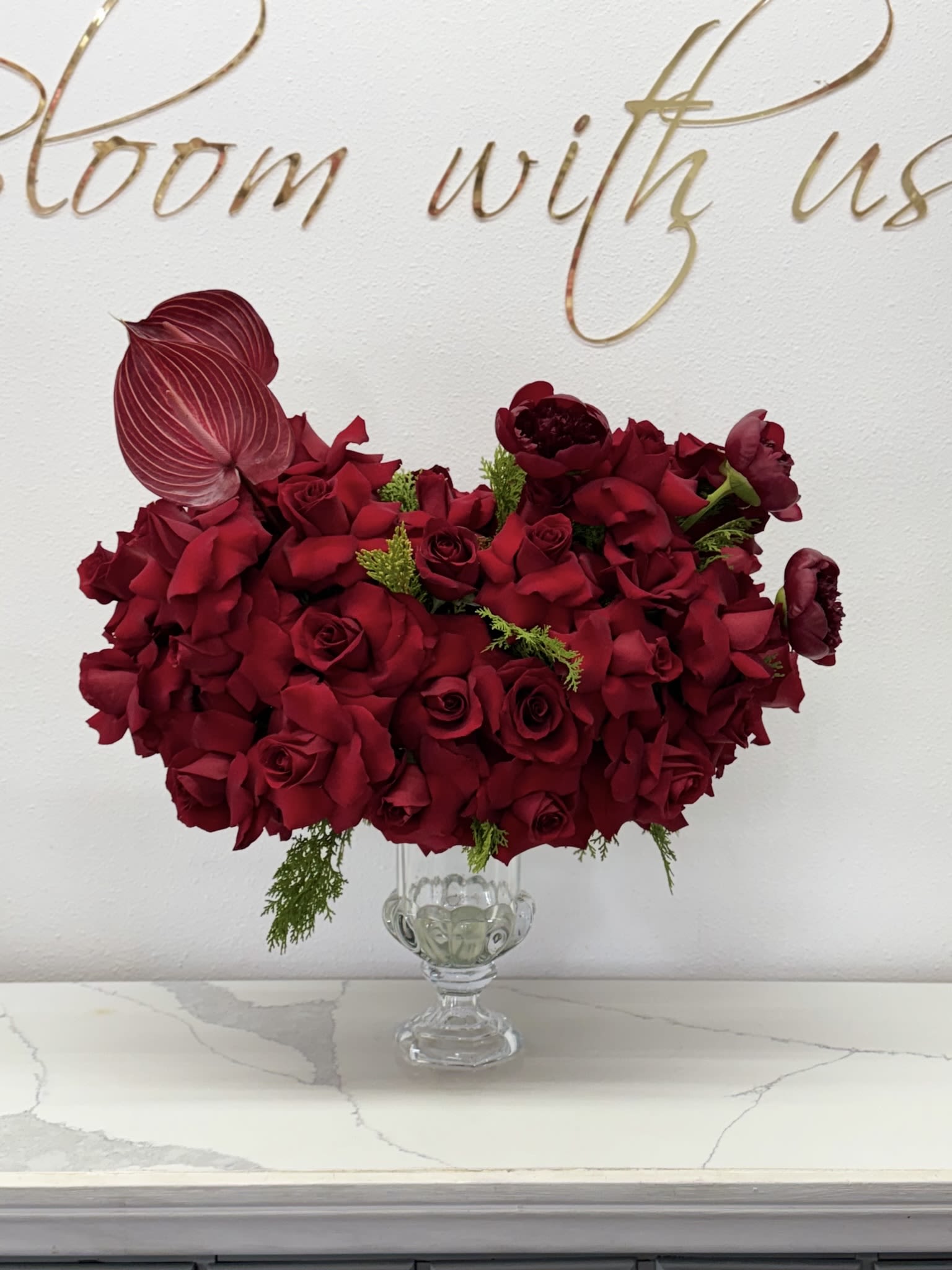  lovers Touhes  - Imagine a stunning arrangement featuring vibrant red roses nestled among delicate peonies, all beautifully displayed in a sleek glass vase. The rich, deep crimson of the roses symbolizes love and passion, creating a striking contrast with the soft, pastel hues of the peonies, which exude elegance and grace. The glass vase enhances the overall aesthetics, allowing the beauty of each bloom to shine through while reflecting light in a mesmerizing dance. This harmonious blend of flowers creates a captivating centerpiece, perfect for any occasion, evoking feelings of warmth and affection. The arrangement is not just a visual treat but also a fragrant delight, combining the sweet, floral notes of peonies with the rich aroma of roses, making it a true feast for the senses.