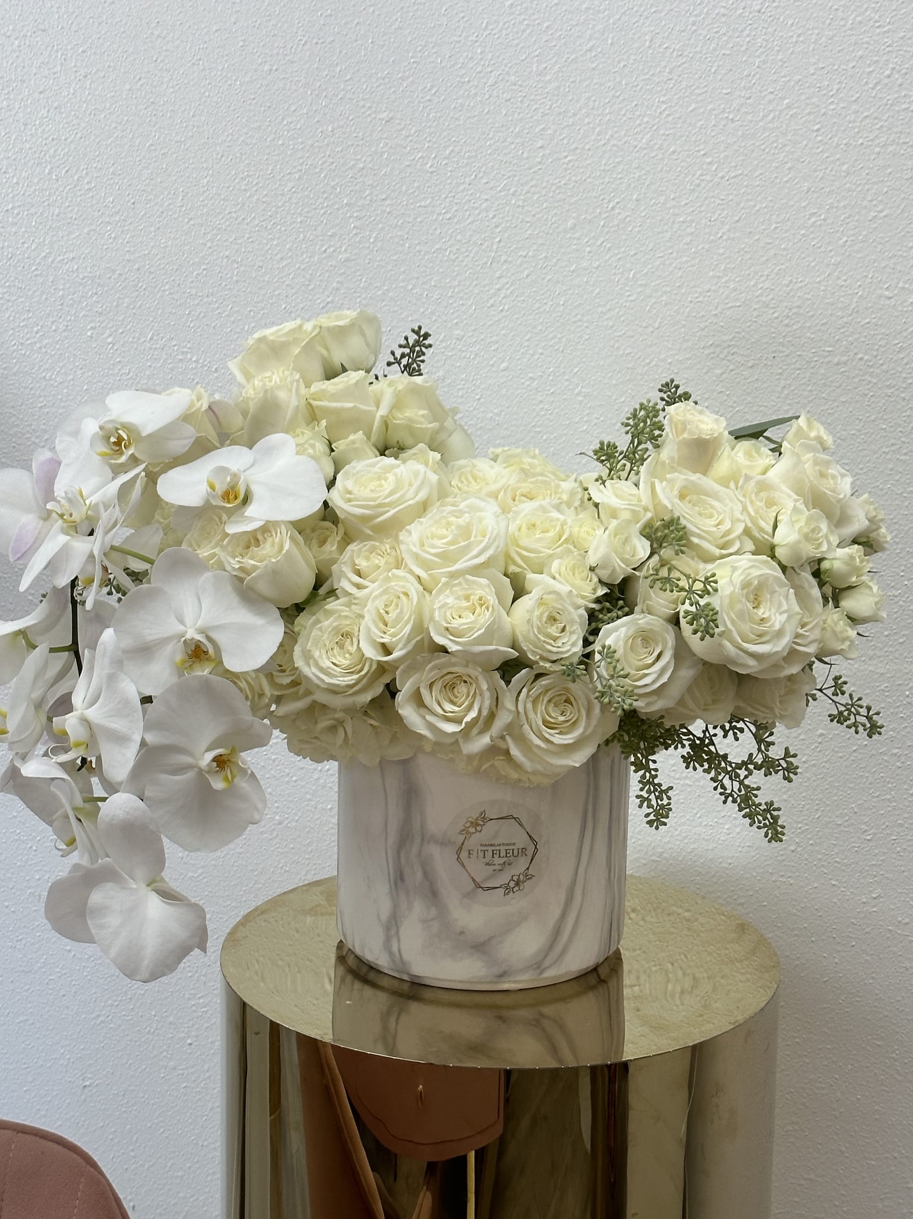 Cascading Clouds  - Bring beauty to the table with elegant arrangement, presented in a round vase. This arrangement features roses and orchids.   Due to the seasonality of flowers or supply chain issues, substitutions may occasionally need to be made. While we understand this is an inconvenience, we will fill your order with an arrangement of similar color and design style.