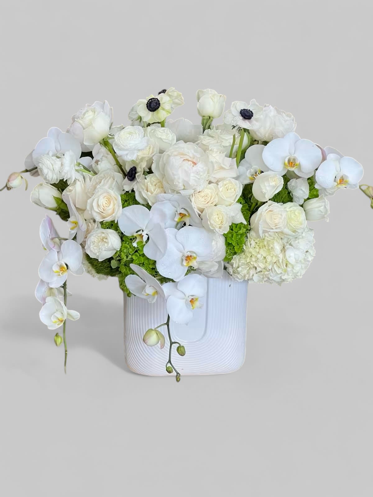 Wistful Whimsy - A sweet and unique arrangement full of hyacinth, tulips, orchids, and accented with succulents and greens ... in a white vase. 