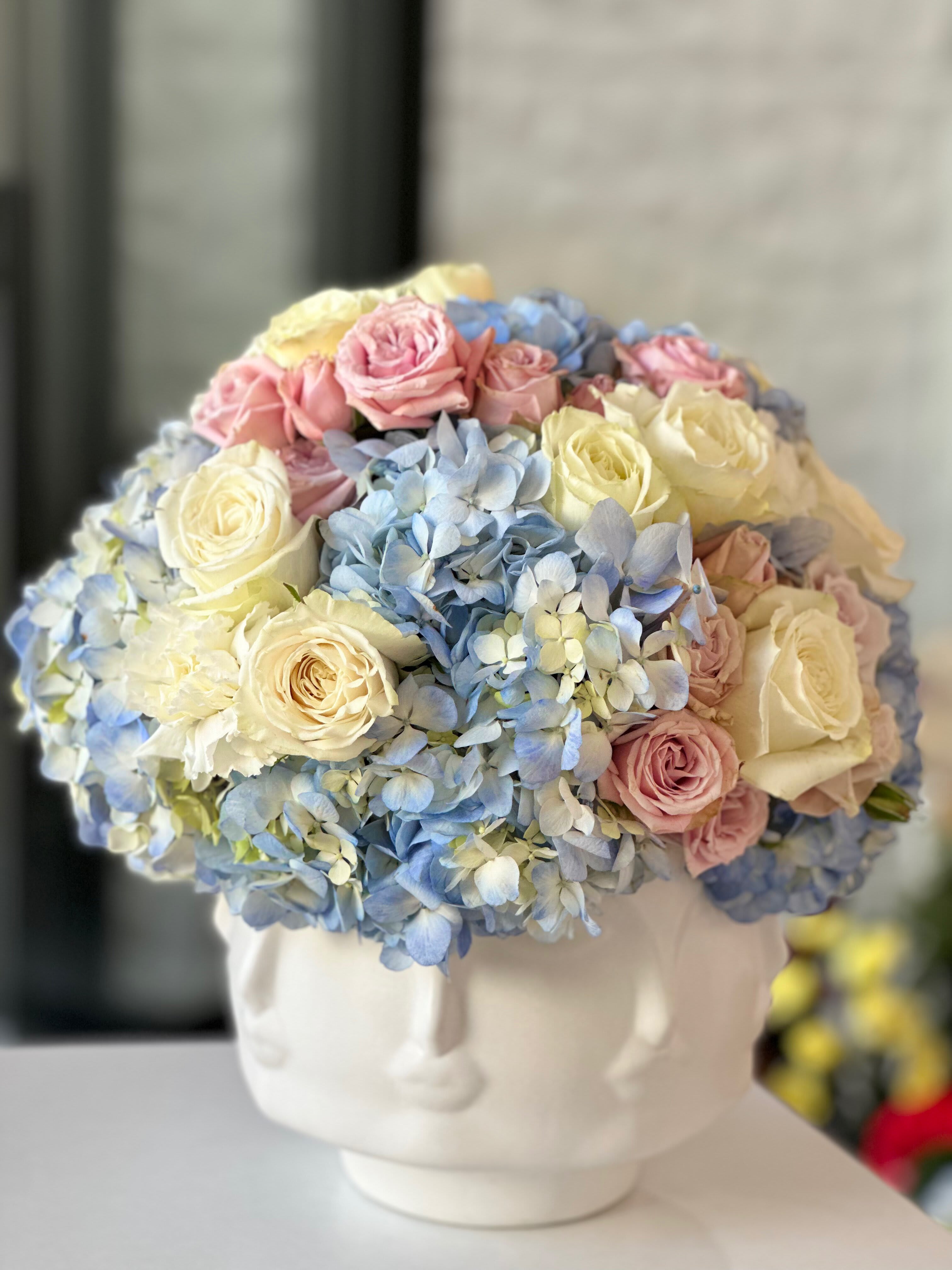 Floral Muse - Introducing the Floral Muse Arrangement—a whimsical and artistic expression of floral elegance. Nestled within a uniquely crafted vase, this arrangement is a celebration of nature's beauty and the captivating charm of artistry. Meticulously chosen blooms intertwine gracefully, complementing the contours of the vessel and bringing the vase to life with a burst of color and fragrance. Ideal for those who appreciate the extraordinary, this arrangement serves as both a visual delight and a captivating home decor piece.  