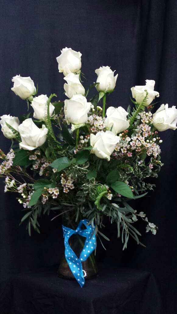 Simple and Serene White Dozen Roses Simple and Serene White Dozen Roses - One dozen premium long stem, white roses beautifully arranged in vase with unique greens and finished with a pretty ribbon.