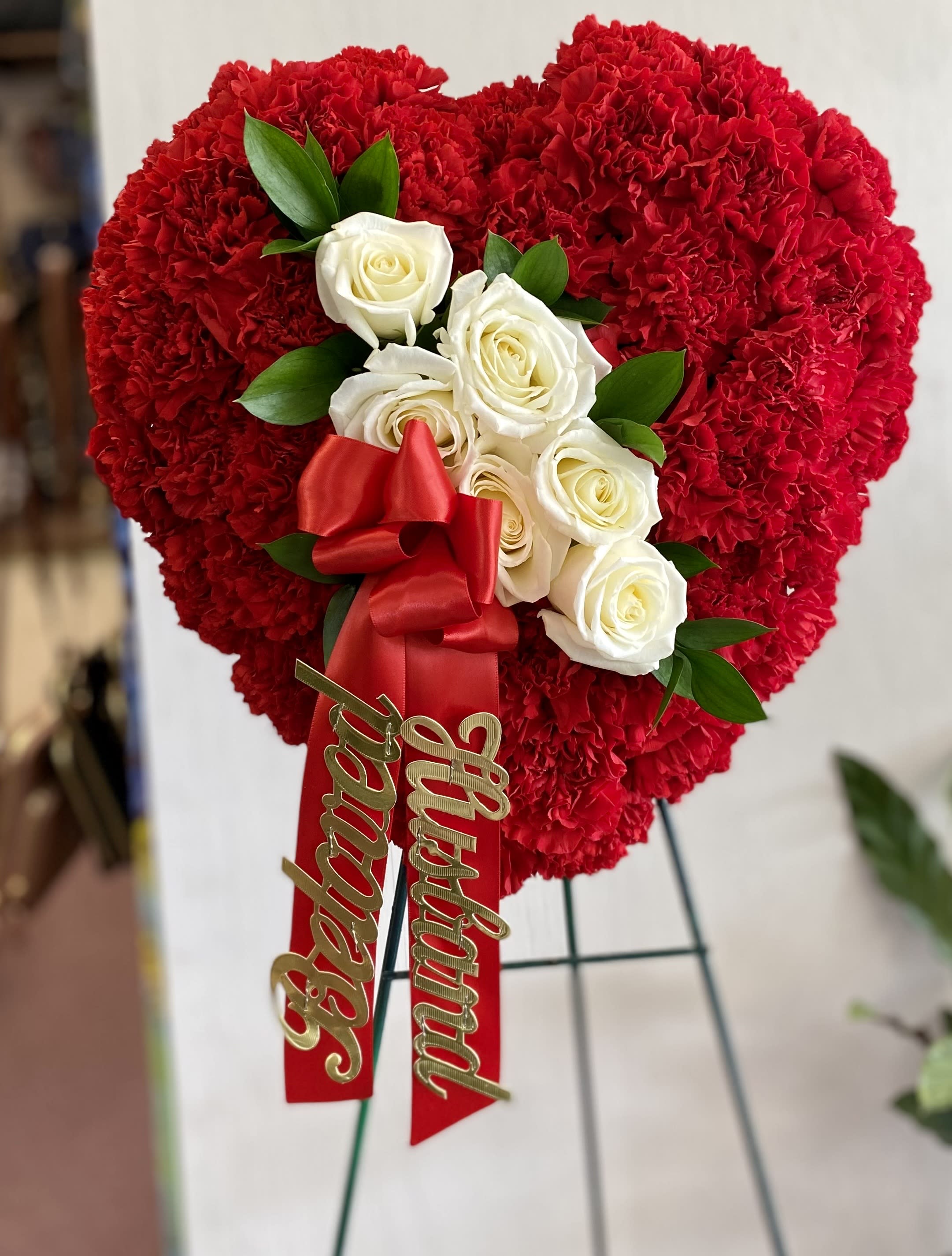 With Much Love - A beautiful, smaller heart. Red carnation background with a spray of white roses. Your choice of banner ... or none at all. Specify in Special Instructions.  Form size 12&quot; wide . Finished size 15-18&quot; wide. 