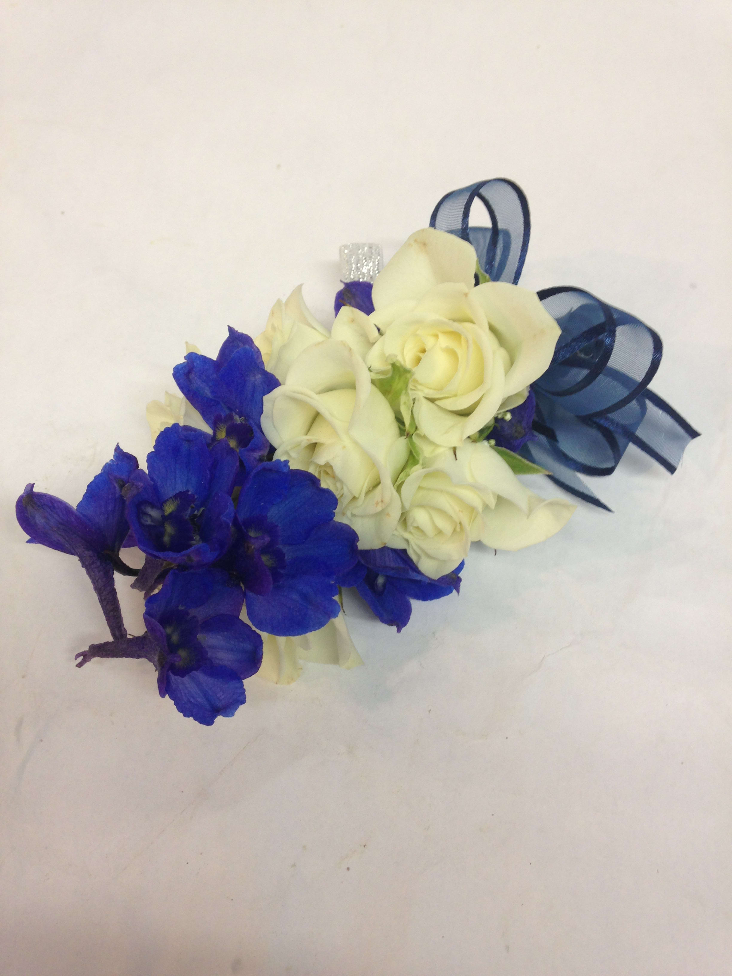 Blue and White Corsage Blue and White Corsage - This modern corsage features crisp blue delphinium paired with white spray roses. Available as a wrist or pin-on corsage. Featured: $38.75