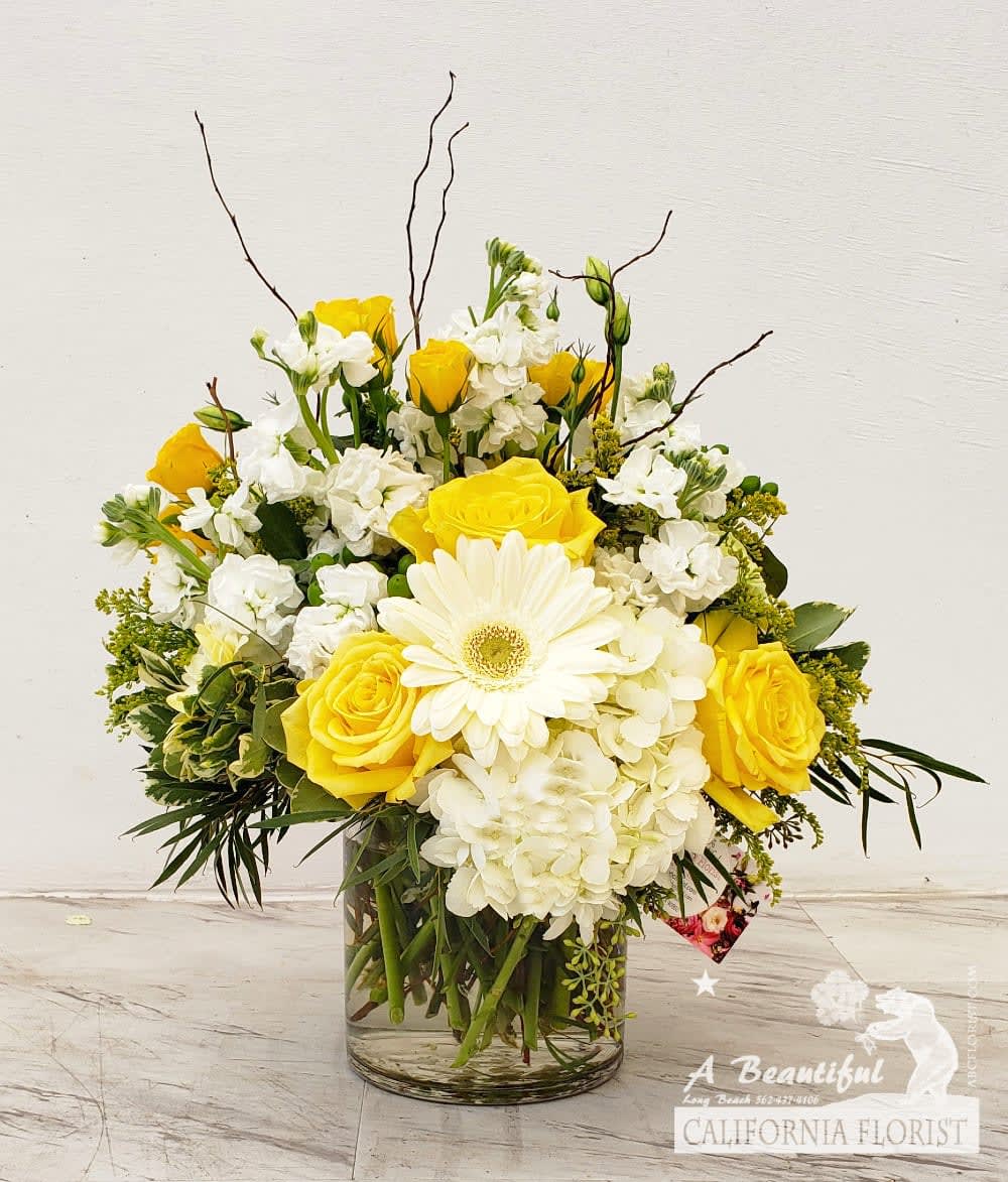 Yellow and White - Soft pastels of yellow and white, understated and elegant. Combined together in florals elements of lush green floliage and accents. Arranged in a clear glass cylinder vase by our artisan florist will convey your feelings of love, caring, comfort or happiness as it works for all occasions.  Approximate size is  12&quot; H x 12 W Yellow and White from Long Beach favorite five 5 star florist offering same day flower delivery A Beautiful California Florist. 
