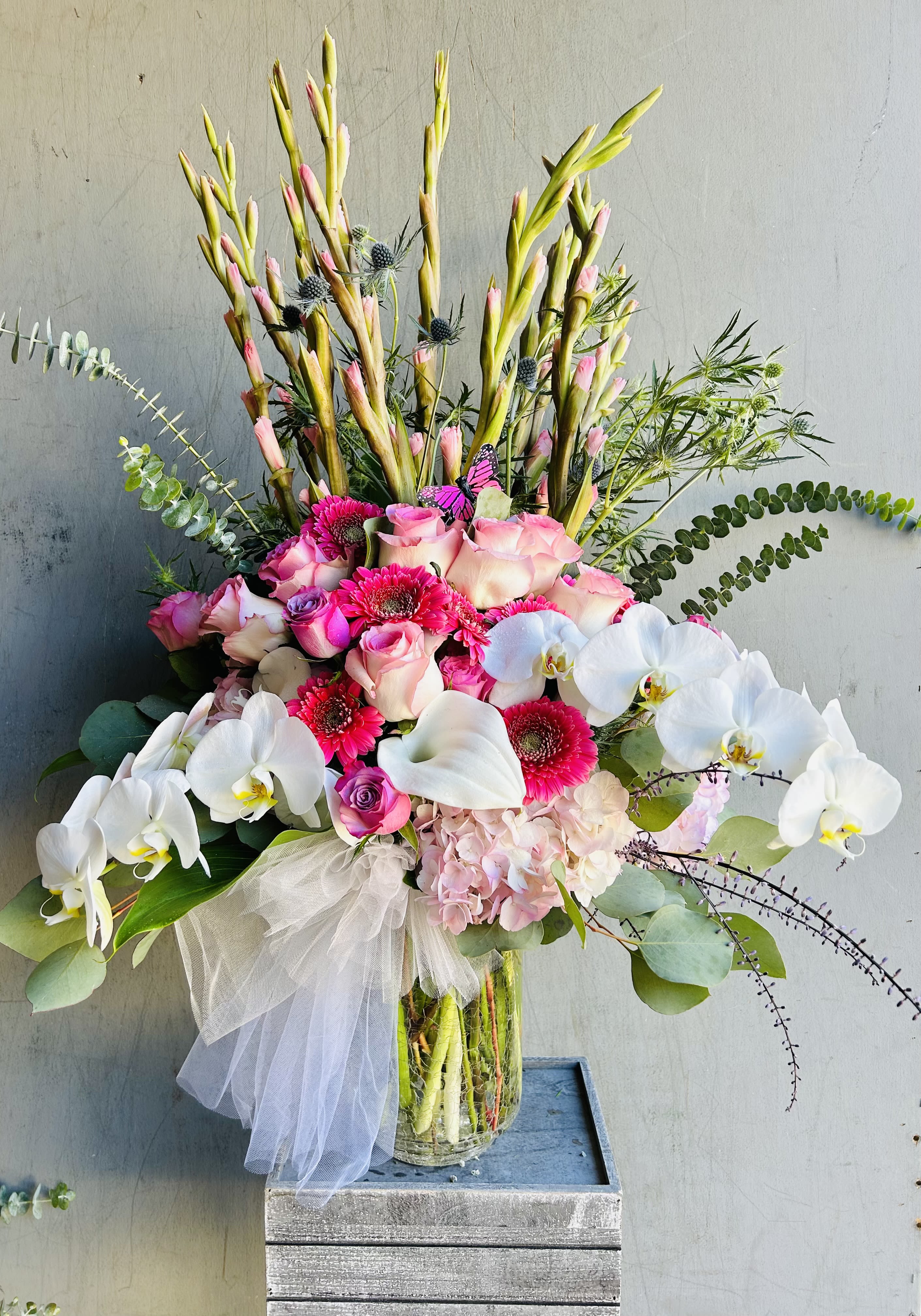 Devotion - Beautiful arrangement featuring roses, chrysanthemum, gladiolus, orchids, and green accents.  