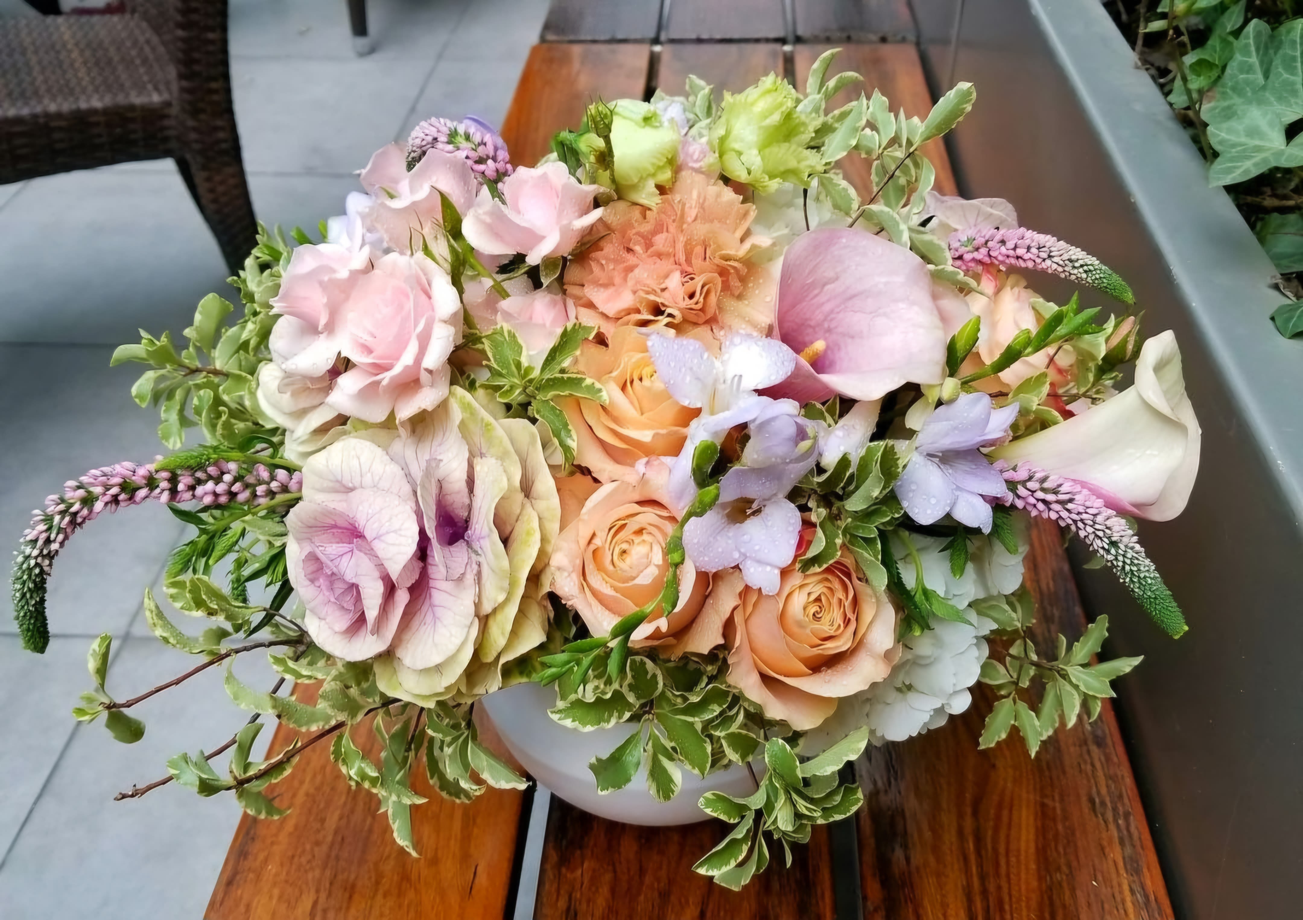 Soft Harvest - The Soft Harvest Arrangement is a breathtaking blend of elegance and tranquility, perfect for celebrating the beauty of fall. Featuring stunning calla lilies and delicate peach roses, this bouquet exudes warmth and sophistication. Soft green accents add a refreshing touch, while ornamental cabbage introduces a unique texture that enhances the arrangement's visual appeal. The harmonious combination of colors and shapes creates a soothing, organic feel, making the Soft Harvest Arrangement an ideal centerpiece for any gathering or a thoughtful gift for someone special. This arrangement beautifully captures the essence of the season, bringing a touch of nature’s artistry into your home.