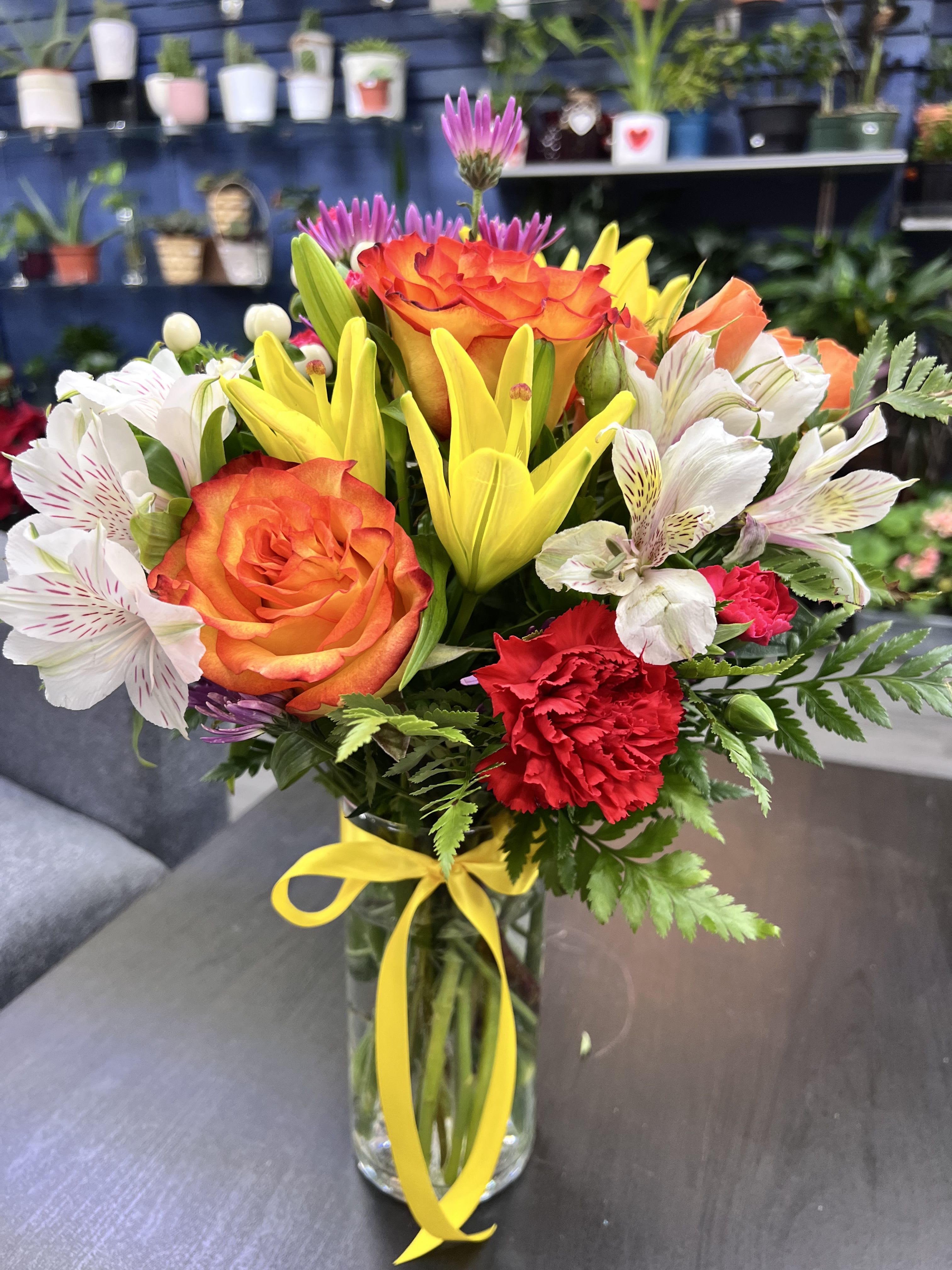 Alegría Floral  - Alegría Floral is a vibrant bouquet full of life, featuring a mix of warm tones in orange, yellow, pink, and more. With lilies, dianthus, mini carnations, and spray roses, this arrangement captures the essence of happiness and freshness. Perfect for brightening any occasion and sending joy and love.