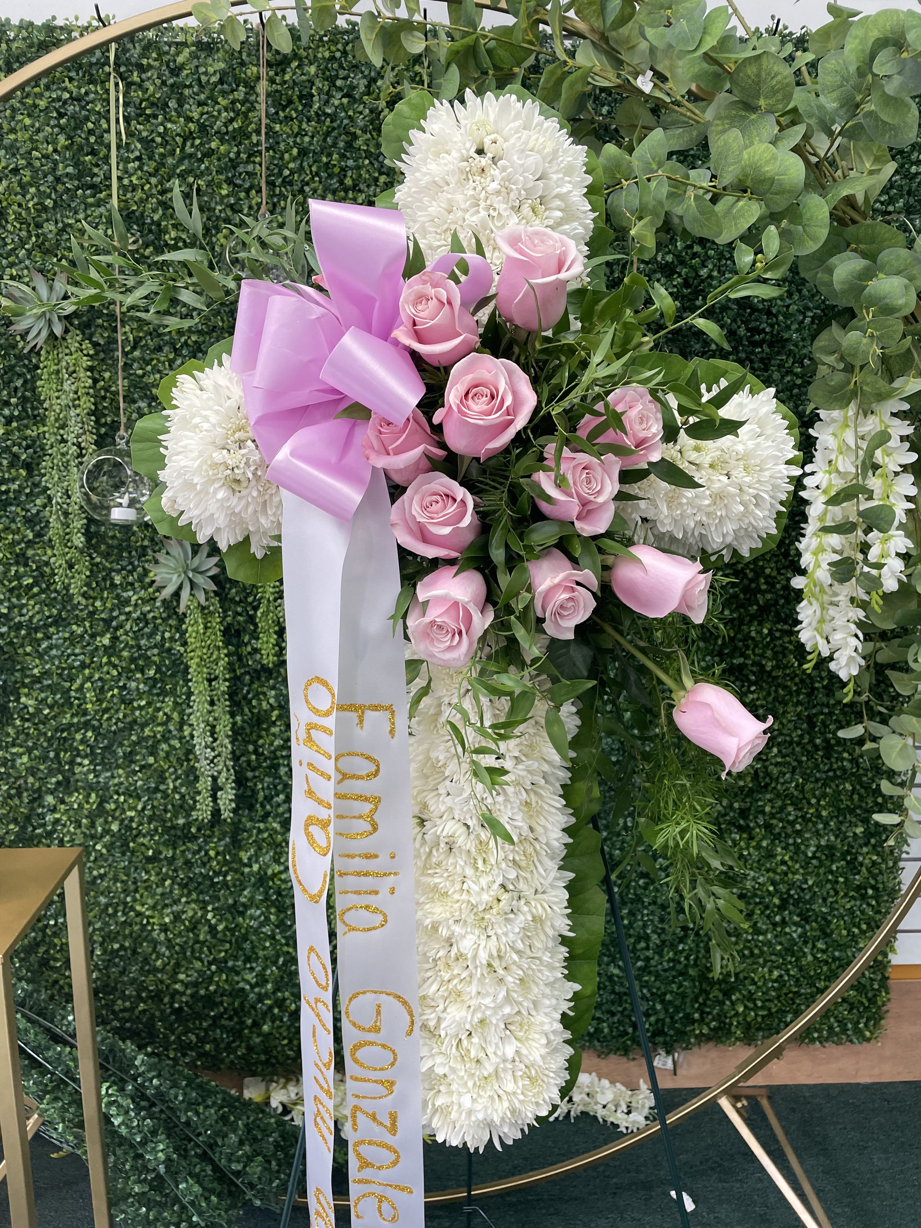 Eterna Serenidad  - Eterna Serenidad is a funeral cross that reflects peace and respect. Featuring white cushion flowers and a delicate center of pink roses, along with a bow and personalized ribbon, this cross is a heartfelt tribute filled with love and comfort, perfect for honoring a loved one. 18”h 