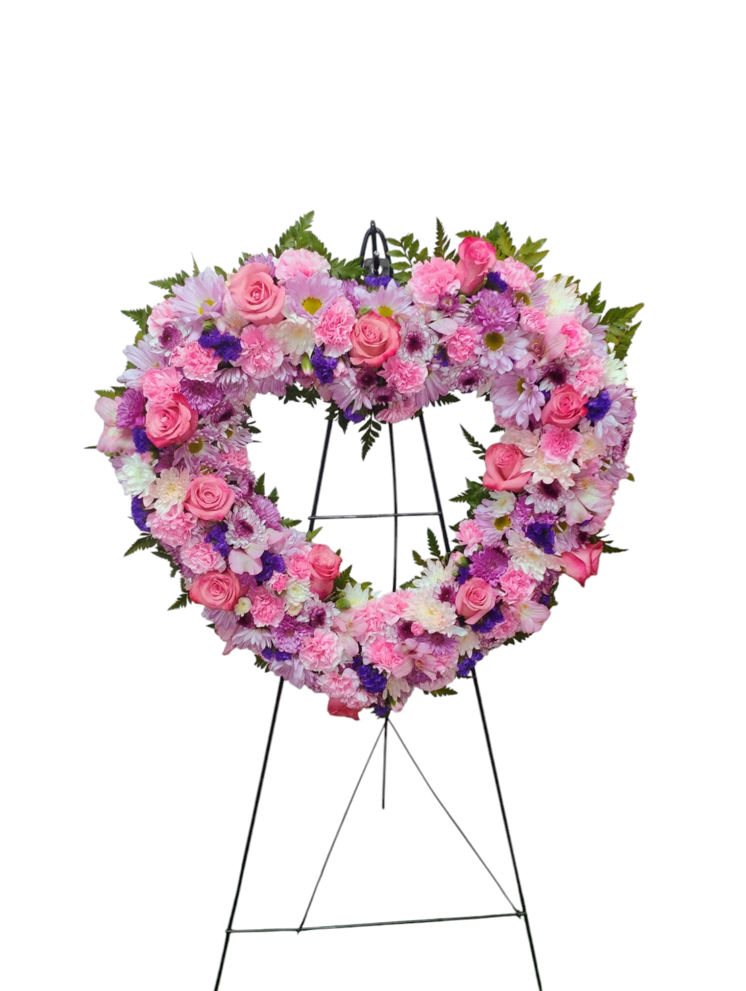 Loves Embrace Arrangement - This exquisite floral arrangement features a vibrant open heart design, artfully crafted with a stunning selection of roses, alstromeria, mini carnations, daisies and poms, all elegantly complemented by lush greens and additional filler flowers. The interplay of colors and textures creates a visually captivating centerpiece that embodies love and affection.  Each arrangement is custom-designed to closely resemble the provided image, ensuring a unique creation tailored specifically for you. It is important to note that due to the natural variability of flowers, some color substitutions may be necessary, and the availability of seasonal blooms may affect pricing. Optional ribbon and script can be added to enhance the presentation, making this floral heart not only a beautiful gift but also a memorable expression of your sentiments.
