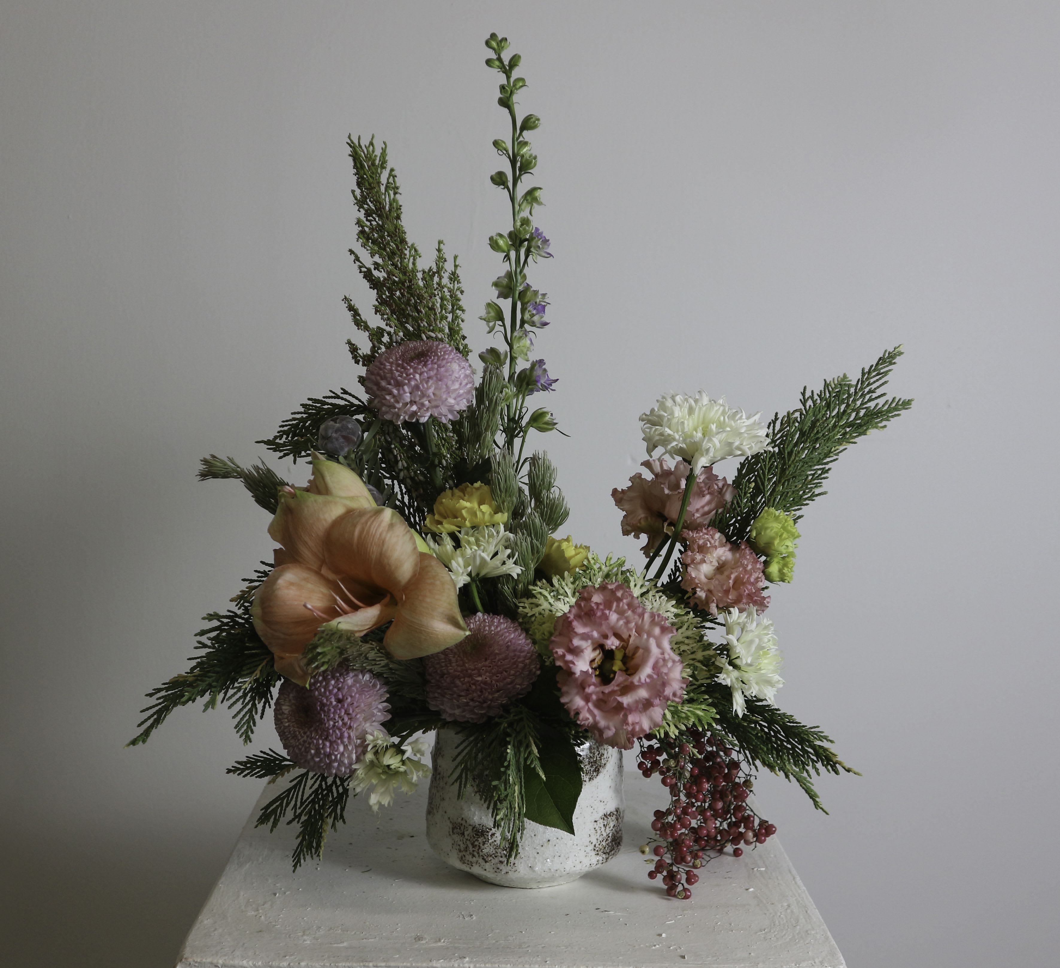 York - Inspired by the charm of York Street in Yangon, this arrangement is a harmonious blend of vibrant textures and delicate hues. Featuring peach amaryllis, soft pink lisianthus, lavender-toned pom-pom chrysanthemums, and cheerful yellow carnations, it is accented with sprigs of lush evergreen and cascading pink pepper berries. Arranged in a rustic, textured vase, &quot;York&quot; exudes a sense of elegance and nostalgia, perfect for evoking warm memories and celebrating moments of beauty.  ---------------------------------------------------  At The Burmese Cat Floral Studio, we celebrate the uniqueness of every flower and vase. While the photo captures the spirit of your arrangement, some elements—like one-of-a-kind vessels or seasonal stems—might not always be exactly the same. However, each arrangement will embody the same charm, elegance, and artistic flair.  If substitutions are needed due to weather, seasonal shifts, or market availability, we’ll stay true to the mood, colors, and style you’ve chosen. Rest assured, any replacements will match or exceed the value of the original design.  If there’s something specific that’s a must-have for your arrangement, just let us know in the notes at checkout or reach out directly—we’ll do our best to make it happen!  ---------------------------------------------------