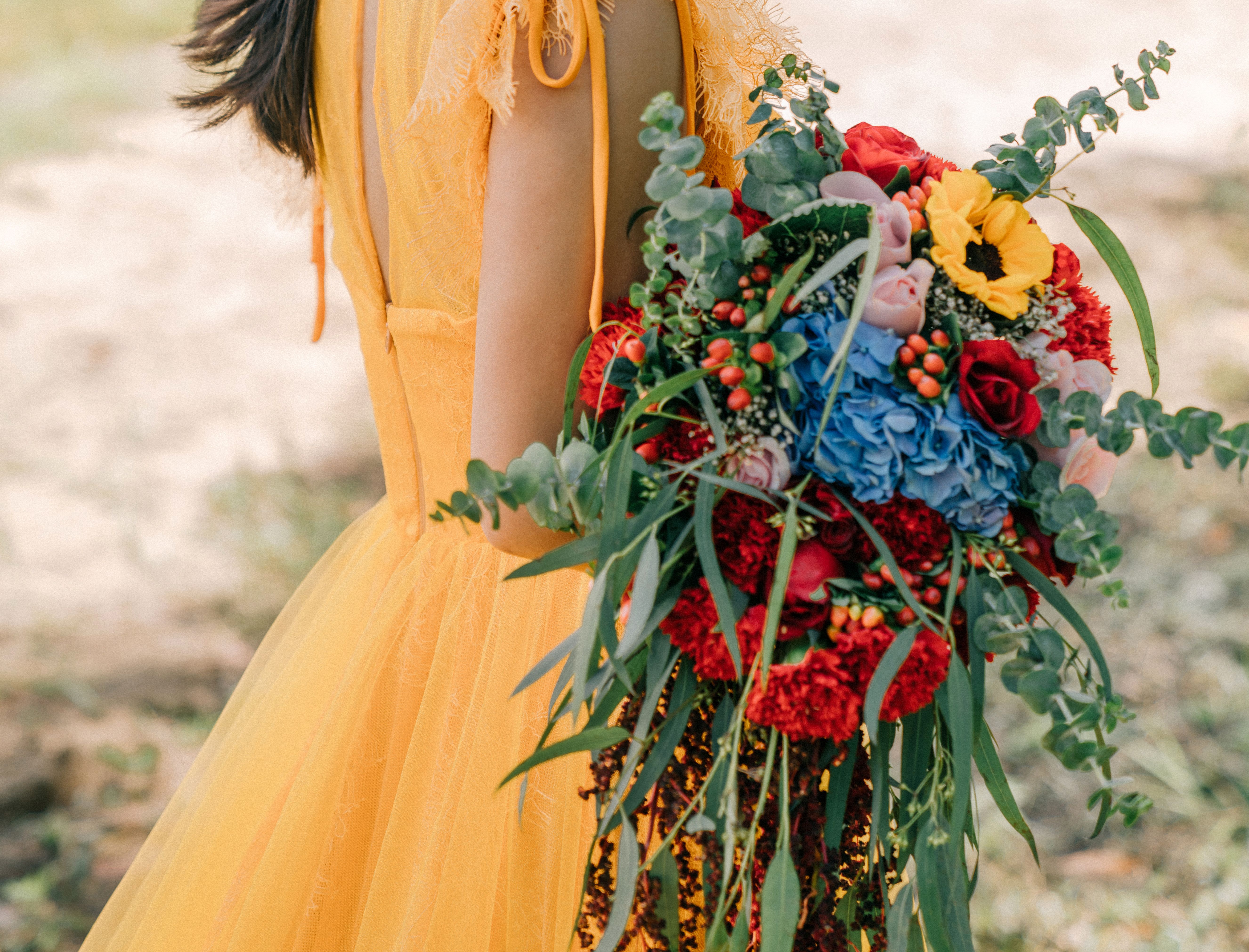 Halpin - Halpin is a bold and vibrant bouquet that radiates joy and energy. Featuring a striking combination of deep red roses, delicate pink blooms, bright sunflowers, and vivid blue hydrangeas, it is accented by lush greenery, eucalyptus, and cascading textures. The dynamic colors and flowing design create a captivating arrangement that perfectly complements a cheerful, sunlit occasion.  ---------------------------------------------------  At The Burmese Cat Floral Studio, we celebrate the uniqueness of every flower and vase. While the photo captures the spirit of your arrangement, some elements—like one-of-a-kind vessels or seasonal stems—might not always be exactly the same. However, each arrangement will embody the same charm, elegance, and artistic flair.  If substitutions are needed due to weather, seasonal shifts, or market availability, we’ll stay true to the mood, colors, and style you’ve chosen. Rest assured, any replacements will match or exceed the value of the original design.  If there’s something specific that’s a must-have for your arrangement, just let us know in the notes at checkout or reach out directly—we’ll do our best to make it happen!