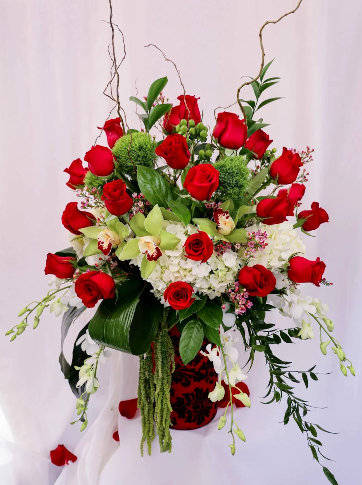 A Million Reasons Why - This grand Valentine's Day arrangement is composed of three dozen roses, hydrangeas, orchids, Italian ruscus, moss and a variety of greens. The arrangement is finished off with a luxurious wrap around a clear crystal vase. 