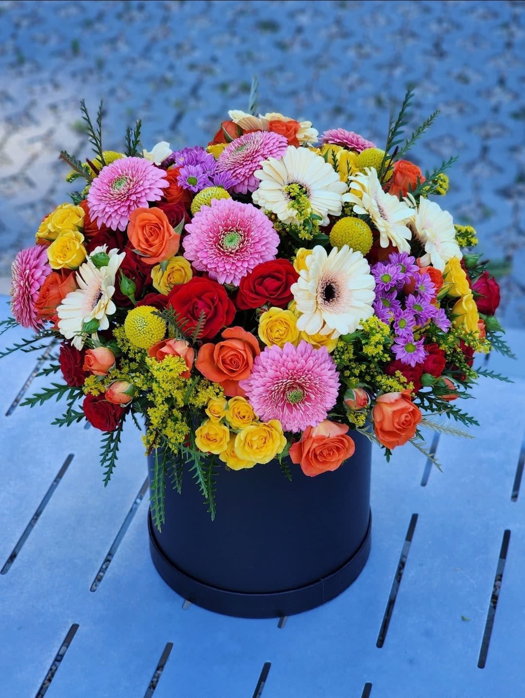Radiant Days - This floral arrangement showcases a vibrant mix of roses, gerberas, presented in a black hatbox. A perfect gift for any occasion. Bring joy and beauty into any space with this exquisite bouquet, designed to impress and delight.