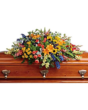  Colorful Reflections Casket Spray by Teleflora - Full of light and love, this colorful casket spray celebrates a bright life with the natural beauty of hydrangea, roses, lilies and sunflowers. Green hydrangea, orange roses, yellow spray roses, orange asiatic lilies, red gladioli, large yellow sunflowers, blue delphinium, orange snapdragons, light yellow stock, purple matsumoto asters, and yellow button spray chrysanthemums are accented with green trick dianthus, blue eryngium, bupleurum, dusty miller, huckleberry, sword fern, lemon leaf. Subject to availability. Substitution policy applies.