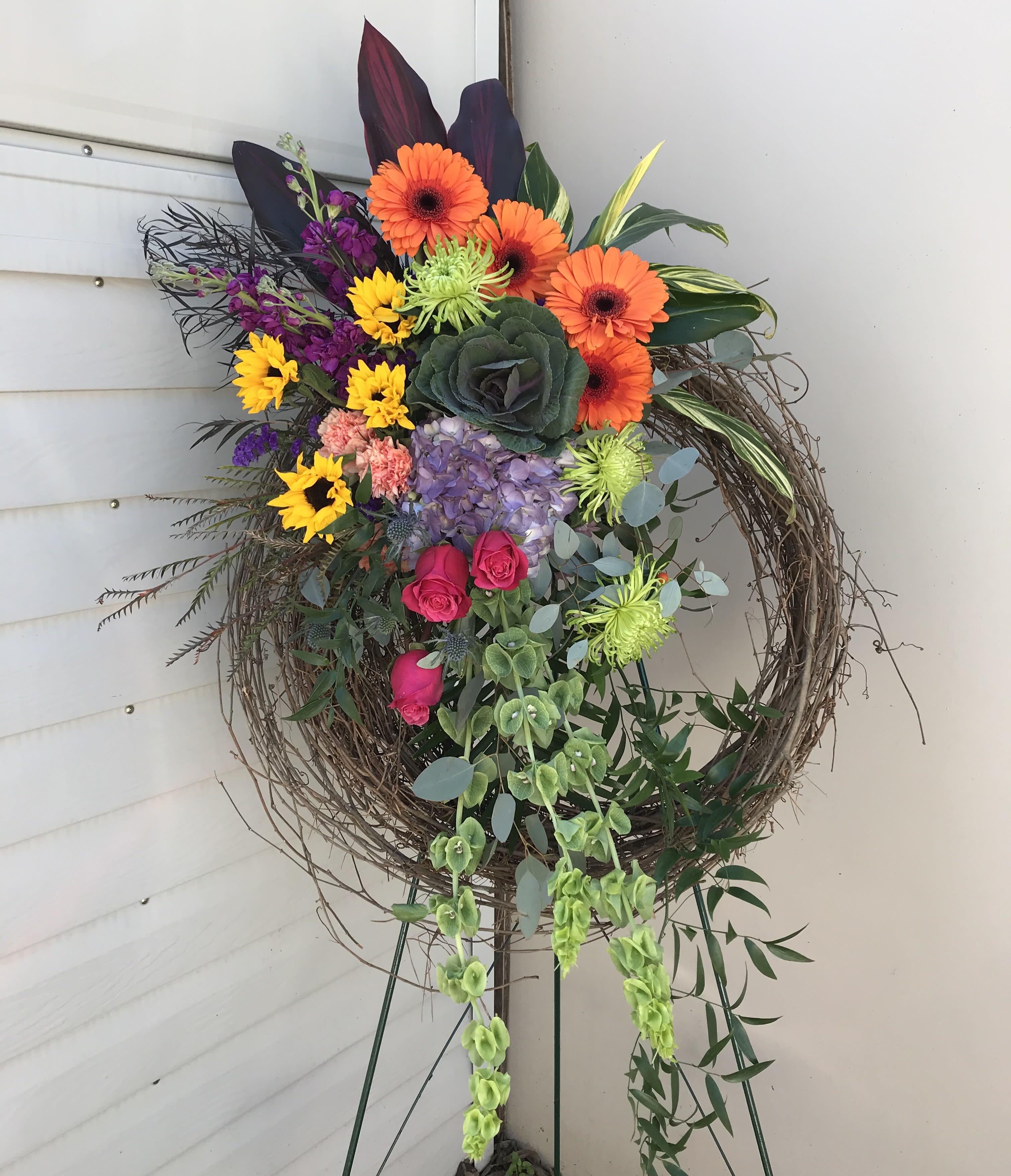 Spring Meadow Grapevine - A grapevine wreath with a beautiful array of bright, bold, flowers. The is designed and delivered on a standing easel. 