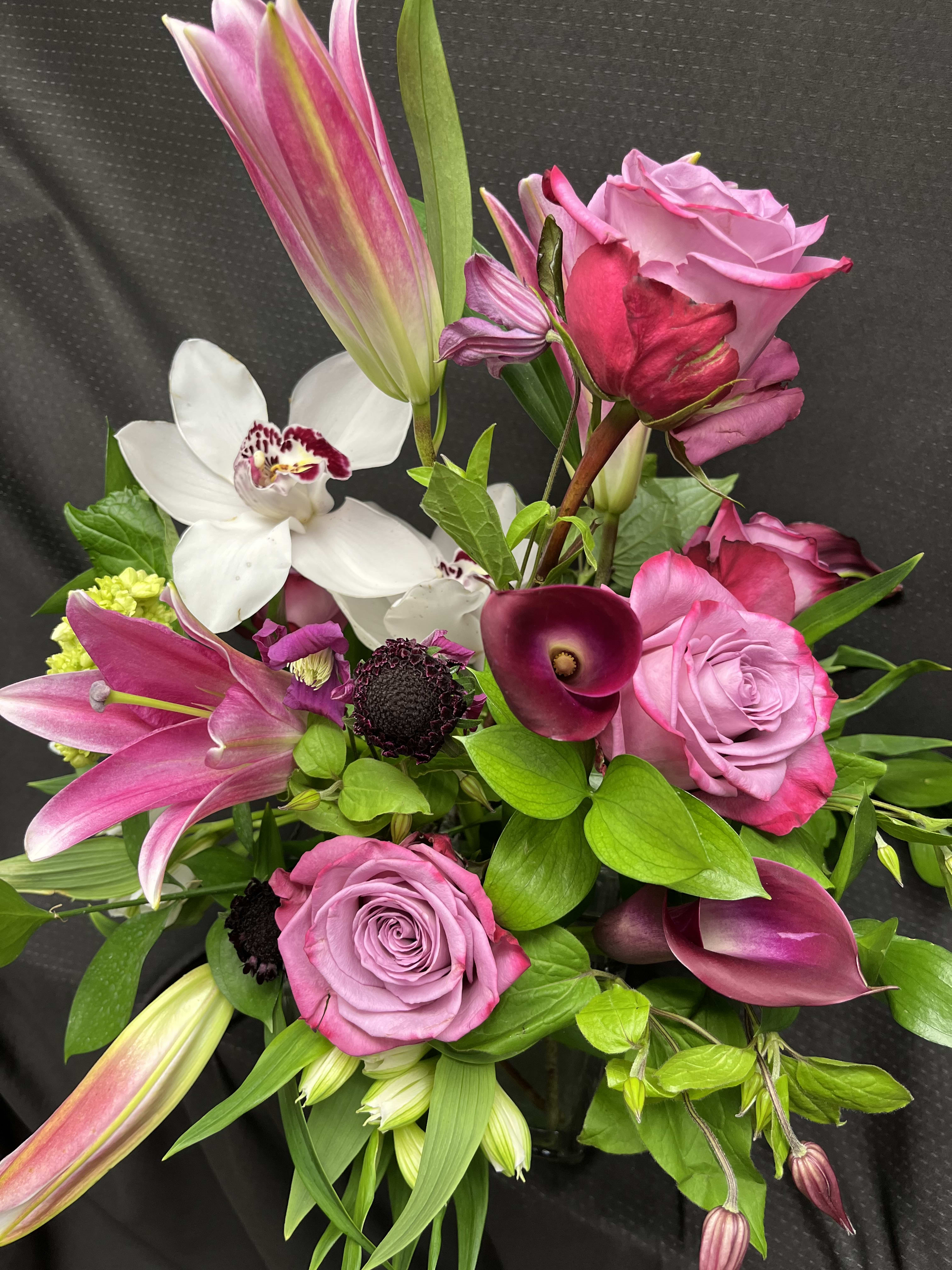 Pretty in Purple - This vase arrangement is made up of lilies, roses, orchids, and calla lilies. 