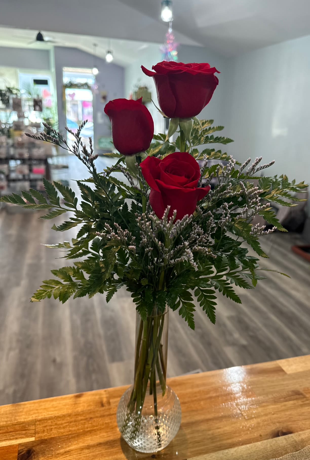 Charming Trio Charming Trio - 3 red roses in lush greens with wisps of limonium for a classic, yet romantic arrangement ***Upgrade to deluxe to add 3 carnations with the roses.