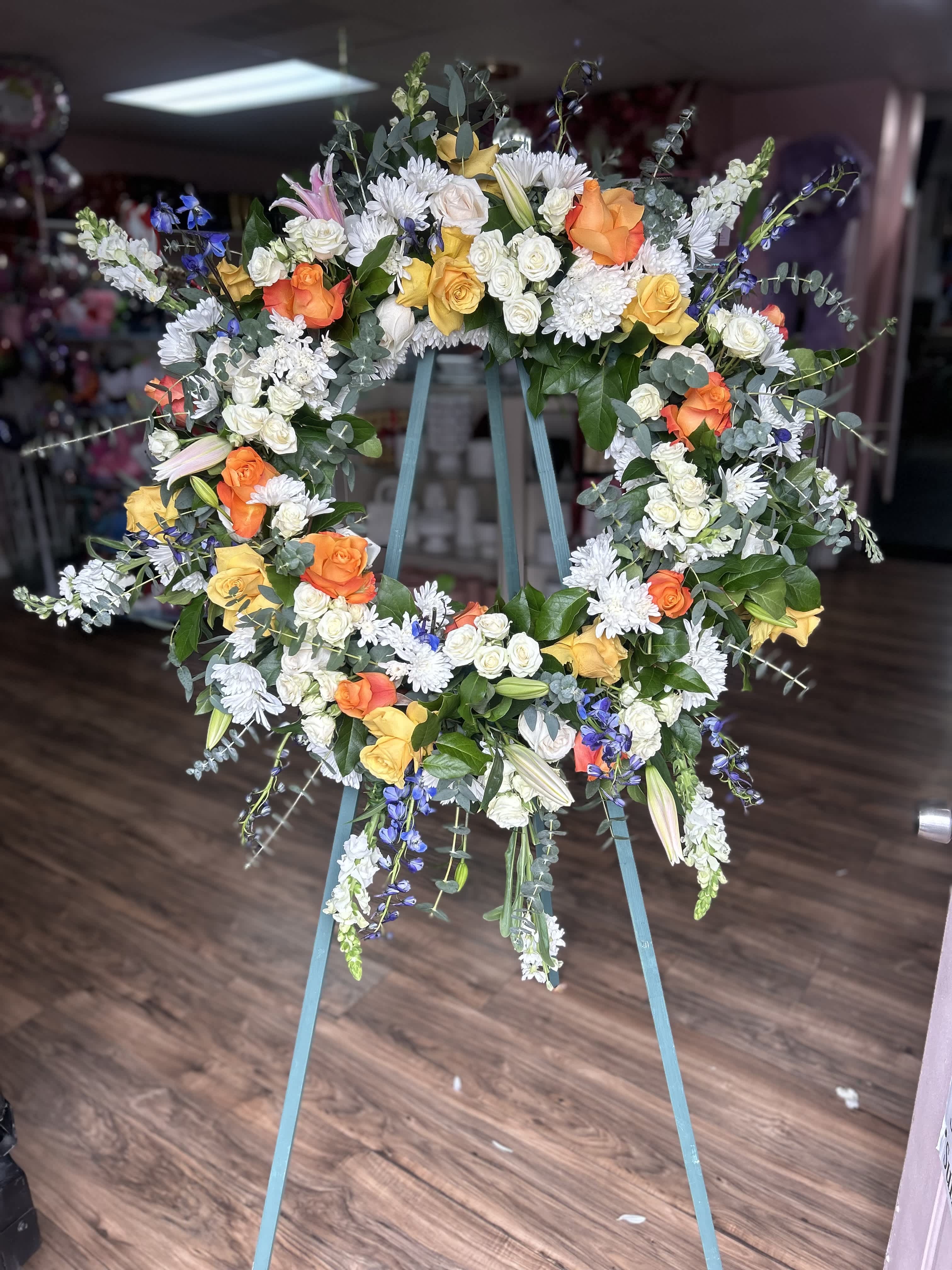 Divine Sympathy Wreath - Family and friends will recollect how special their loved one was with this gentle and timeless circle of fragrant blooms to celebrate sweet memories.   - a mixture of roses, spray roses, eucalyptus, snap dragon, delphinium, pompom and stock.