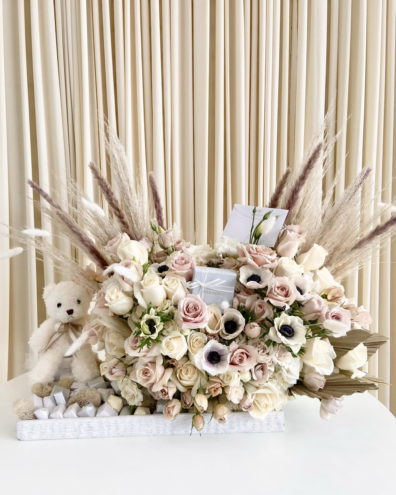 Hello World - Welcome their new bundle of joy with this breathtaking gift arrangement that includes  a keepsake bear they can keep forever.   (Gift box in center of arrangement &amp; chocolates are not included but can be provided by the customer)