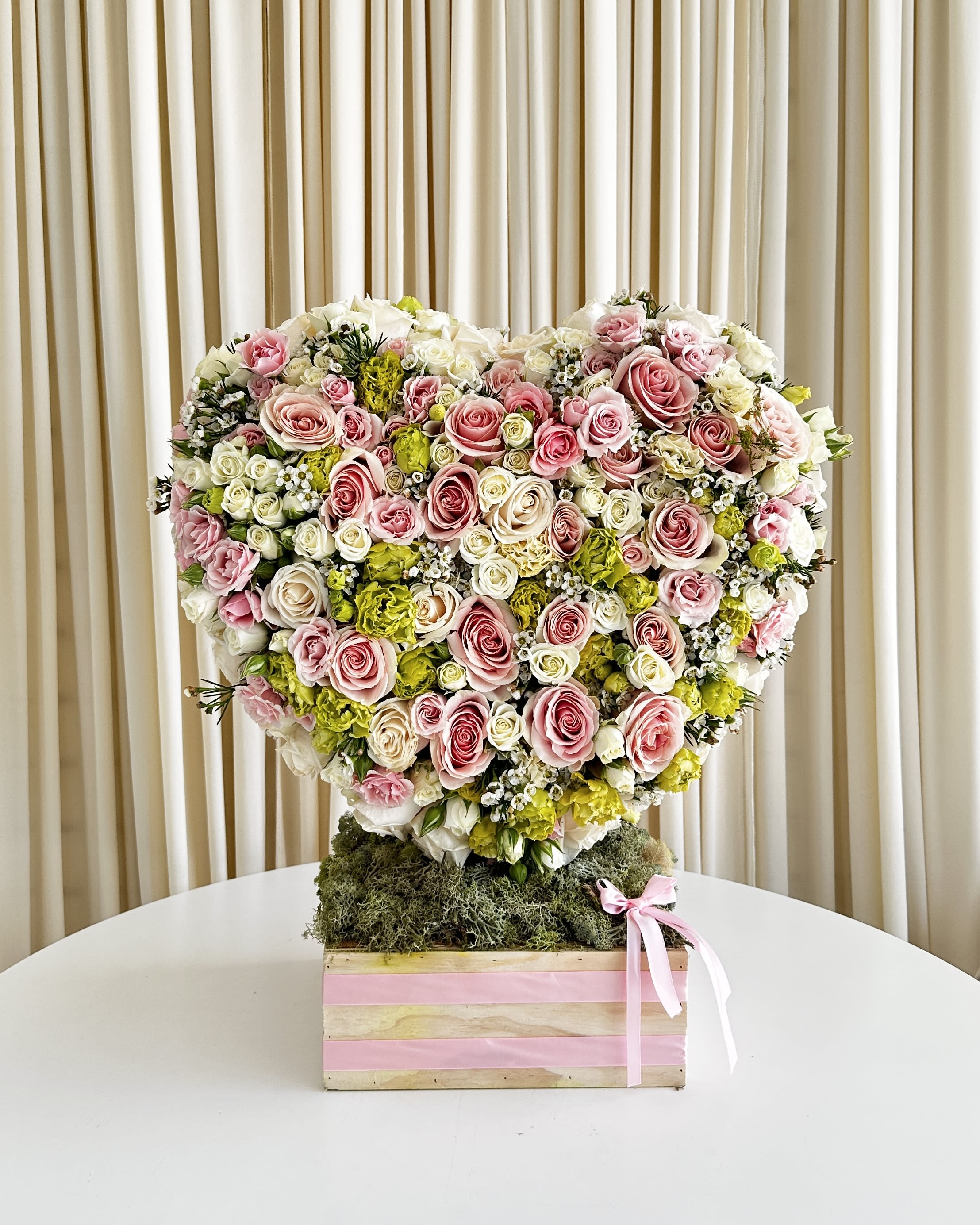 Eternal Love Blossom - Embrace the language of flowers with our exquisite &quot;Eternal Love Blossom&quot; heart-shaped floral arrangement. This captivating creation is a symphony of nature's finest hues, blending delicate shades of pink, pure whites, and captivating greens into a harmonious floral arrangement that speaks volumes of love and devotion.  Crafted by our skilled florists with meticulous care and attention to detail, the &quot;Eternal Love Blossom&quot; is not just a floral arrangement; it's a heartfelt expression of your deepest emotions. Each petal and leaf has been thoughtfully chosen and arranged to convey the purity of white blooms, the tenderness of pink petals, and the vibrancy of fresh greenery.  This enchanting arrangement is more than just a gift; it's a message from the heart. Whether you're celebrating an anniversary, expressing your affection on Valentine's Day, or simply letting someone know how much they mean to you, the &quot;Eternal Love Blossom&quot; is the perfect choice.