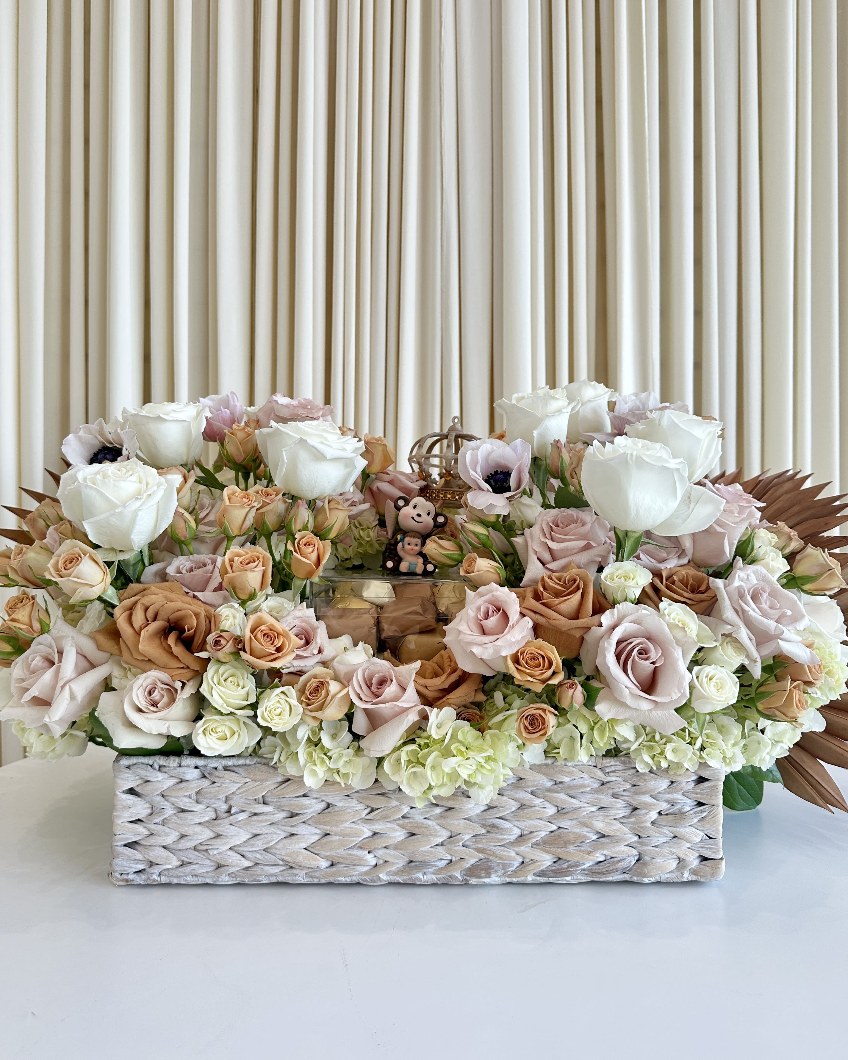 Blossoming Elegance - !!!Chocolates &amp; items in tray not included but can be provided by customer!!! Indulge your senses in a symphony of beauty and flavor with our &quot;Blossoming Elegance&quot; flower arrangement. This exquisite creation combines the timeless allure of neutral-colored roses, delicate anemones, lush hydrangeas, and captivating rust-colored accents, meticulously arranged in a basket weave design vase.  At Amaranthine LA, we believe in elevating the ordinary into the extraordinary, and &quot;Elegance in Bloom&quot; embodies that philosophy. Each flower in this arrangement is carefully selected to exude a sense of sophistication and grace, making it the perfect gift for any occasion.  But that's not all; our &quot;Elegance in Bloom&quot; arrangement also includes a delightful selection of luxury chocolates. These chocolates are more than just confectionery; they're an exquisite pairing with the floral arrangement. The chocolates are elegantly presented alongside the flowers, creating a harmonious blend of visual and gustatory pleasure.  Whether you're expressing your love, appreciation, or simply treating yourself, &quot;Elegance in Bloom&quot; is the ultimate gesture of refinement and taste. Elevate your moments with this luxurious combination of nature's beauty and the sweet indulgence of gourmet chocolates. 