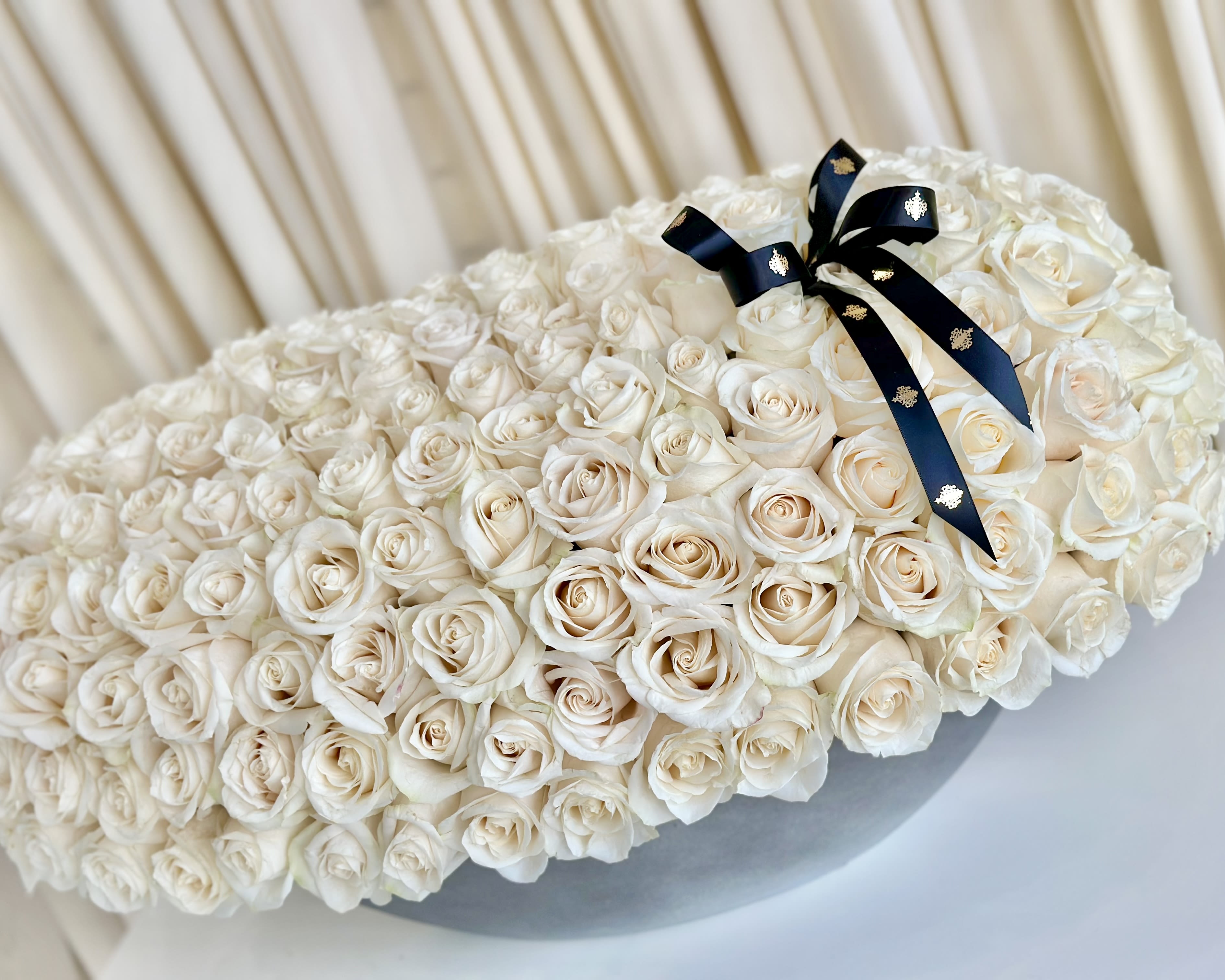 Whispering Petals - Experience the enchanting allure of our &quot;Whispering Petals&quot; White Rose Arrangement. Delicate and elegant, this stunning display features a collection of ivory white roses presented in a modern vase. Each blossom whispers tales of grace and tenderness, symbolizing purity and new beginnings. Grace your space with this timeless arrangement, and let the subtle beauty of &quot;Whispering Petals&quot; infuse your surroundings with an air of sophistication and serenity. Perfect for honoring special moments or conveying heartfelt emotions, these white roses create an ambiance of tranquility and understated charm.