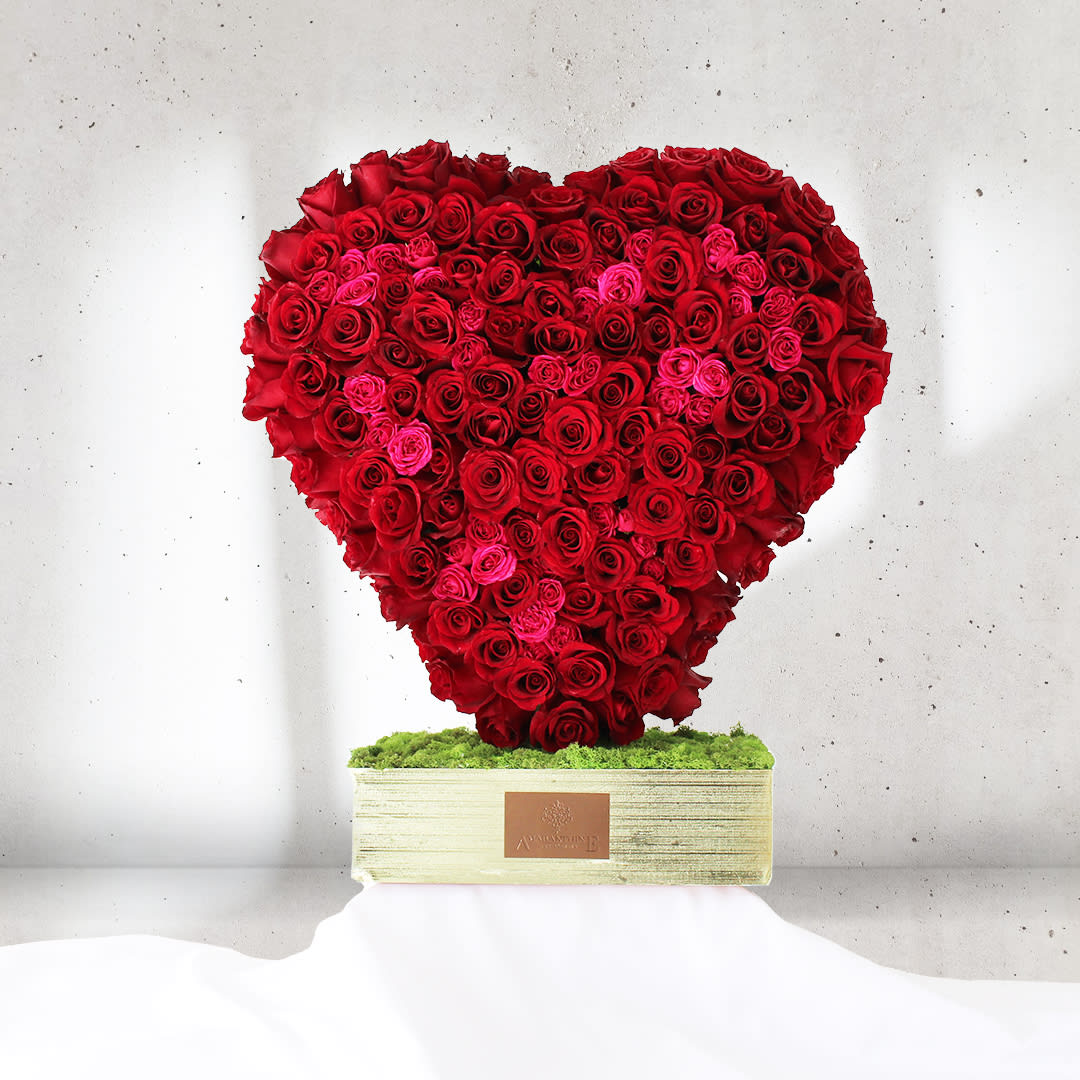 Passionate Heartbeat Passionate Heartbeat - Surrender to the rhythm of "Passionate Heartbeat," a breathtaking flower arrangement that embodies the fiery spirit of love. Designed in a grand heart shape, this captivating display is adorned with an abundance of bright red and fuchsia roses, igniting a symphony of intense emotions. The vibrant red roses symbolize boundless love and desire, while the striking fuchsia roses exude an air of exuberance and charm. Together, they create a powerful expression of passion and devotion, captivating the heart with their vibrant hues. "Passionate Heartbeat" becomes an enchanting centerpiece, radiating love and joy in any setting. Perfect for celebrating special occasions, anniversaries, or expressing your deepest affections, this grand heart-shaped arrangement conveys a love that beats with a fervent intensity.