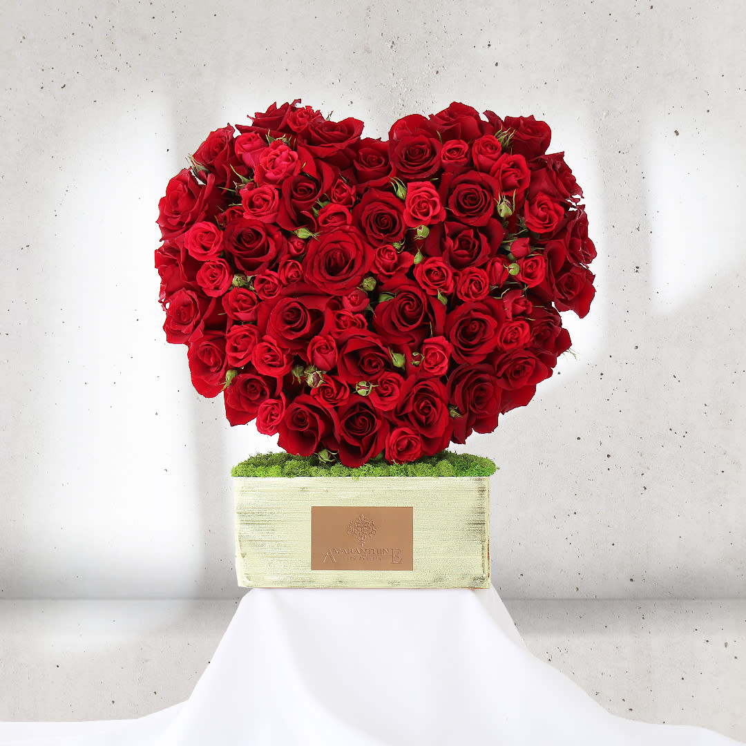 Scarlet Love Affair - Surrender to the passion and romance of &quot;Scarlet Love Affair,&quot; a captivating heart-shaped flower arrangement adorned entirely with deep crimson red roses. This exquisite display of affectionate beauty speaks of timeless love and devotion.  Each red rose symbolizes a fiery love, embodying the profound emotions that reside within the heart. The heart shape, a universal symbol of love, amplifies the sentiment, making &quot;Scarlet Love Affair&quot; a perfect gift to express your deepest affections and devotion to someone special.