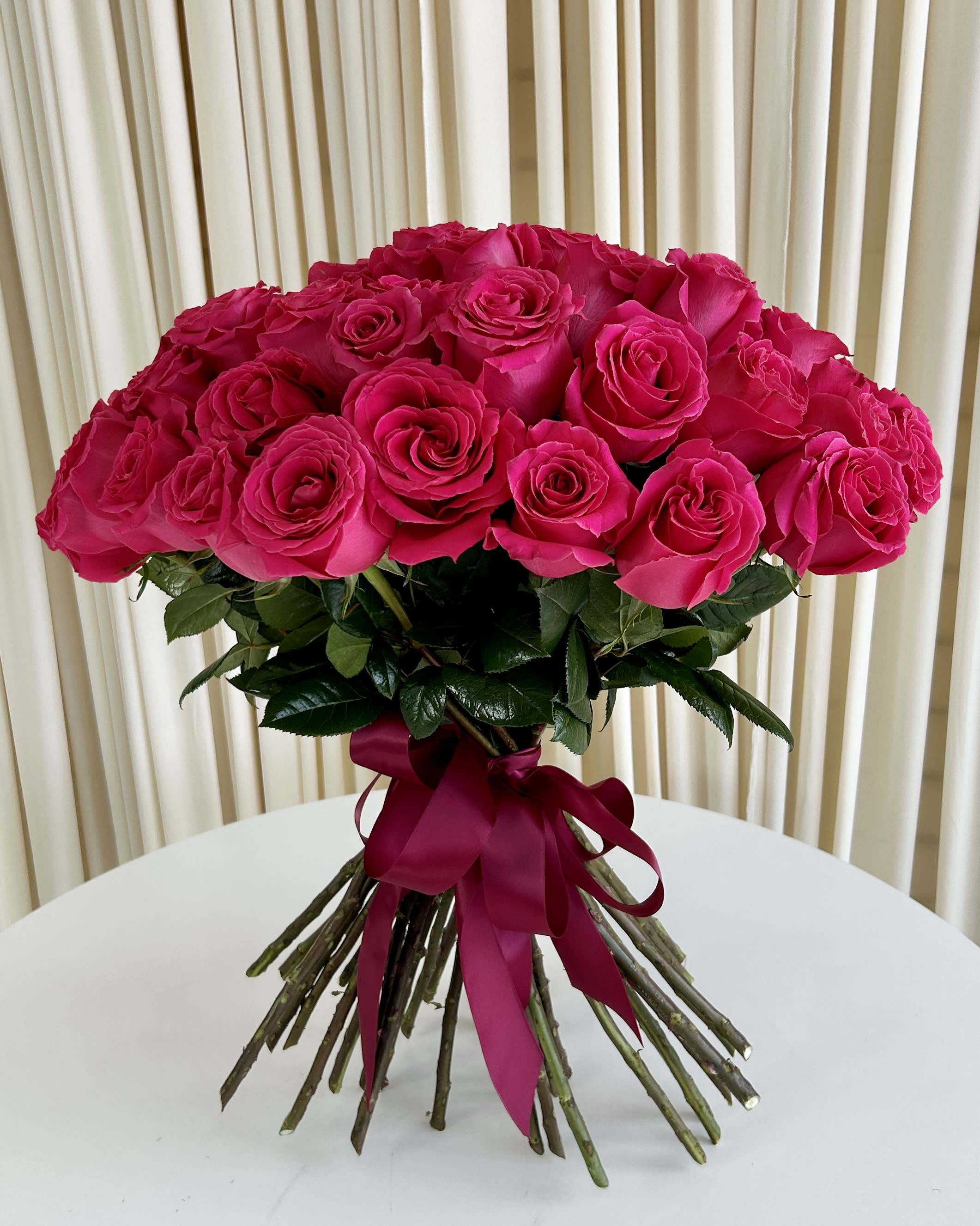 Pink Passion Pink Passion - Experience the electrifying "Pink Passion" Hot Pink Rose Bouquet, where vibrant hues and romantic charm unite in a breathtaking display. This enchanting arrangement showcases a collection of sizzling hot pink roses, elegantly tied together with a rich burgundy ribbon. Each hot pink rose exudes energy and excitement, symbolizing admiration and appreciation. The captivating color contrast of the roses against the deep burgundy ribbon creates a striking visual harmony, evoking a sense of timeless allure and passionate emotions.