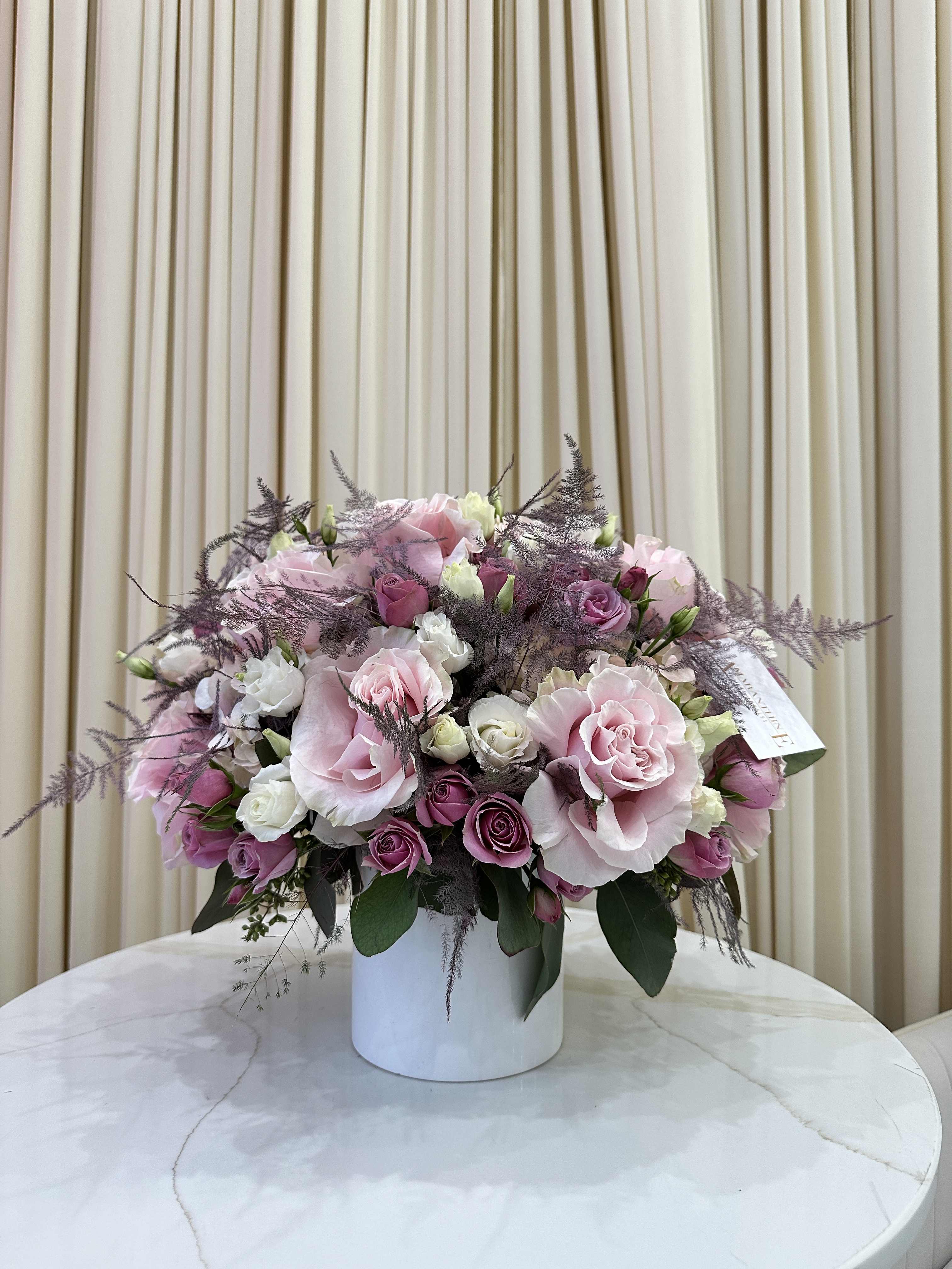Pastel Paradise - Bring a touch of springtime indoors with this cheerful arrangement of pastel-colored blooms. Featuring pink and lavender roses, hydrangeas, and lisianthus, accented with pops of greenery, this arrangement is sure to brighten any day.