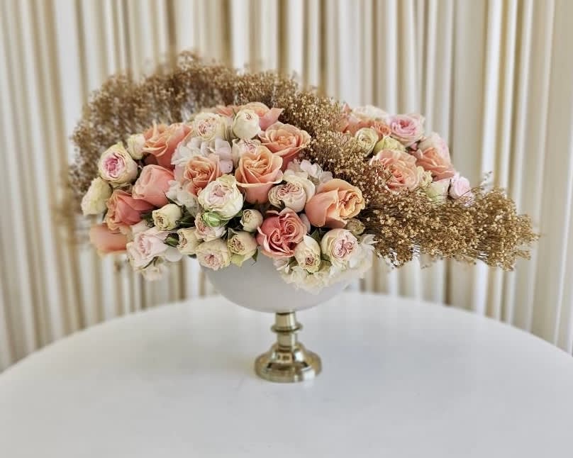 Peachy Perfection Peachy Perfection - Discover the epitome of floral elegance with our "Peachy Perfection" arrangement. Radiating in soft, inviting peachy tones, this exquisite display captures the essence of grace and beauty. Dried flowers artfully accentuate the arrangement down the middle, adding a touch of charm and whimsy to the composition. Nestled in a beautiful vase, "Peachy Perfection" showcases the subtle hints of garden roses, elevating the arrangement to a whole new level of sophistication. Each bloom and dried element harmonize flawlessly, presenting a visual symphony of textures and colors.