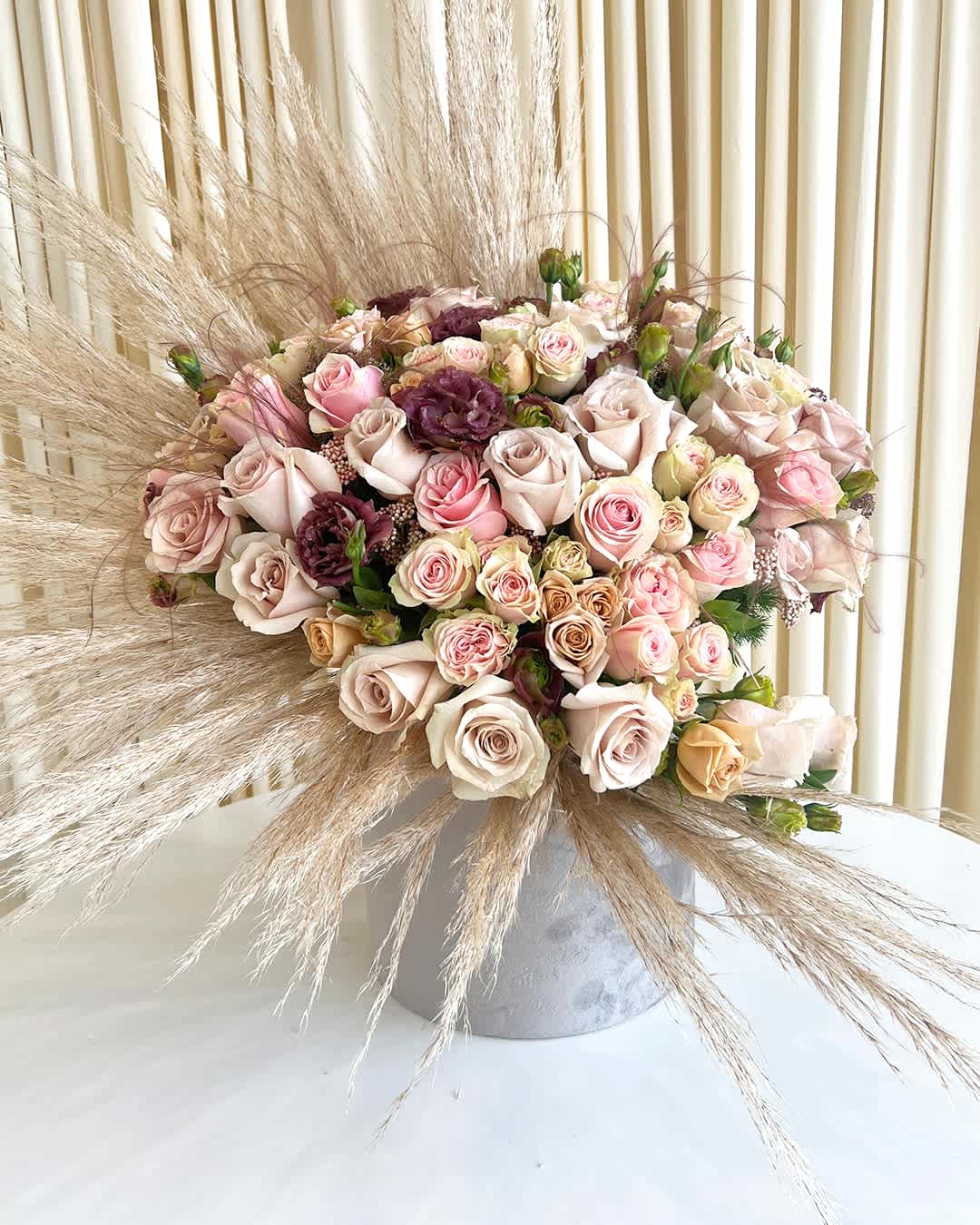 Autumn Whisper - Embrace the serene beauty of &quot;Autumn Whisper,&quot; a captivating flower arrangement that harmoniously blends neutral fall colors with subtle touches of muted purple and pinks. This stunning display captures the essence of the season, creating a sense of warmth and tranquility.  Rich earthy tones of caramel, rust, and golden hues set the autumnal stage, while the gentle addition of muted purple and soft pinks add a delicate and sophisticated charm. The arrangement exudes a sense of balance and elegance, mirroring the changing colors of fall leaves as they gracefully dance in the breeze.