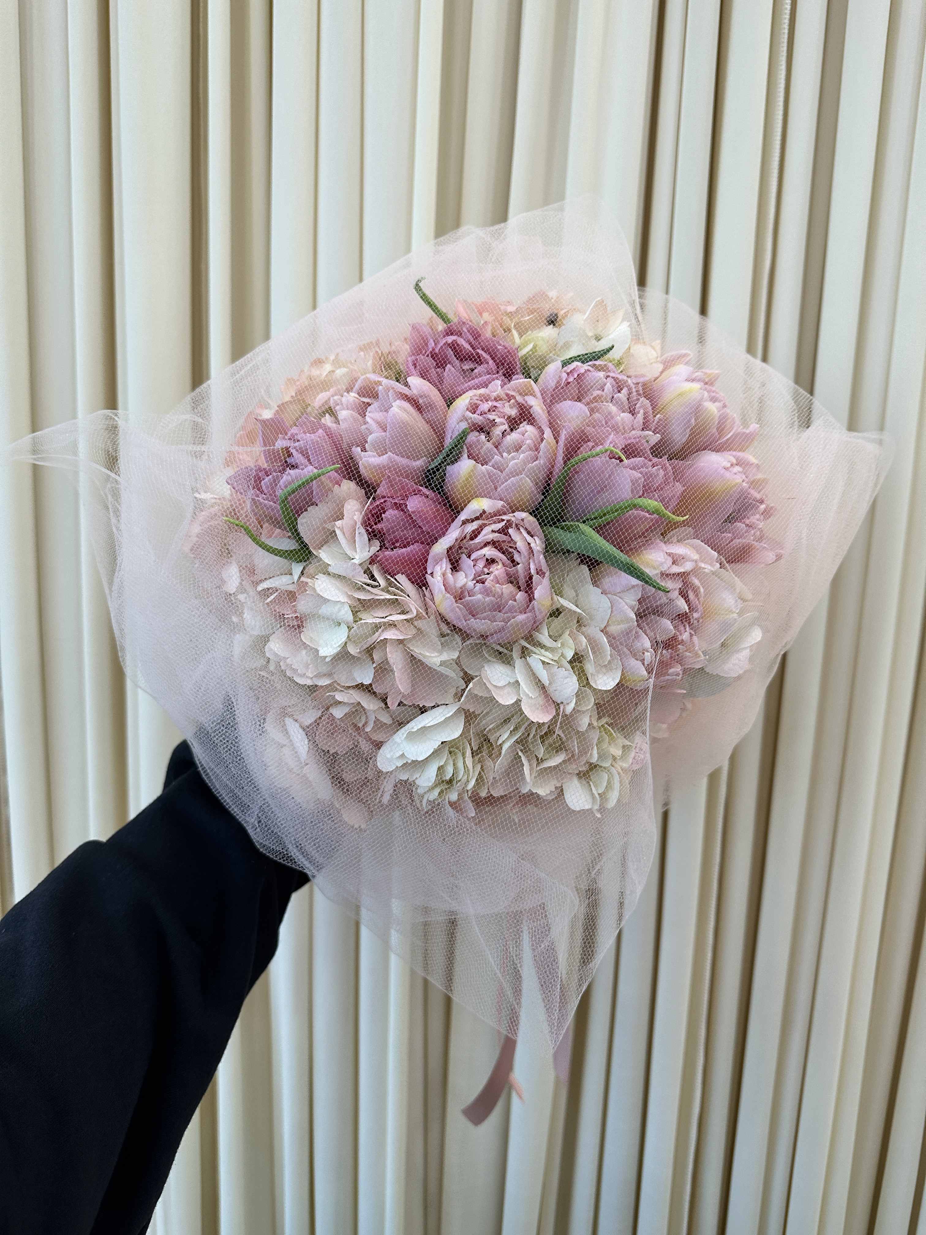 Springtime Delight - This vibrant bouquet captures the essence of spring with a delightful mix of tulips and hydrangeas. The tulips, with their tall stems and cup-shaped blooms, symbolize perfect love and new beginnings. The hydrangeas, with their fluffy, rounded clusters of flowers, represent gratitude and heartfelt emotions. Together, these blooms create a stunning and symbolic arrangement that is perfect for any occasion.