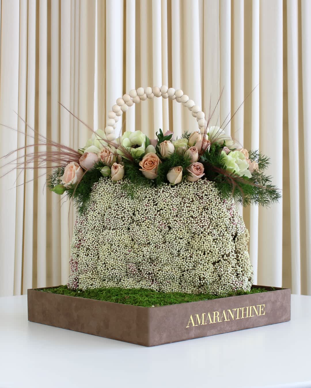 Blooms in Vogue Floral Purse Blooms in Vogue Floral Purse - Elevate your floral gifting game with our "Blooms in Vogue Floral Purse" – a masterpiece that combines the artistry of fashion with the beauty of nature. This unique flower arrangement is a splendid representation of elegance and creativity, meticulously crafted to resemble a stylish purse. Whether you're celebrating a special occasion, expressing your love, or simply looking for a one-of-a-kind gift, the "Blooms in Vogue Floral Purse" is the perfect choice. Its distinctive design sets it apart from traditional flower arrangements, making it a conversation starter at any event or gathering. This artistic floral purse is not just a gift; it's a work of art that embodies the essence of beauty and sophistication. Make a statement that goes beyond words with the "Blooms in Vogue Floral Purse" – because true luxury is in the details, and nature's beauty knows no bounds.